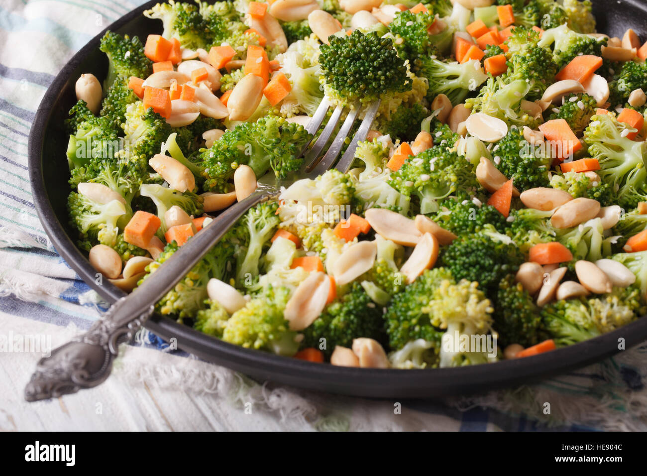 Gesunder Salat mit Brokkoli, Karotten und Erdnüssen Nahaufnahme auf einer Platte. horizontale Stockfoto