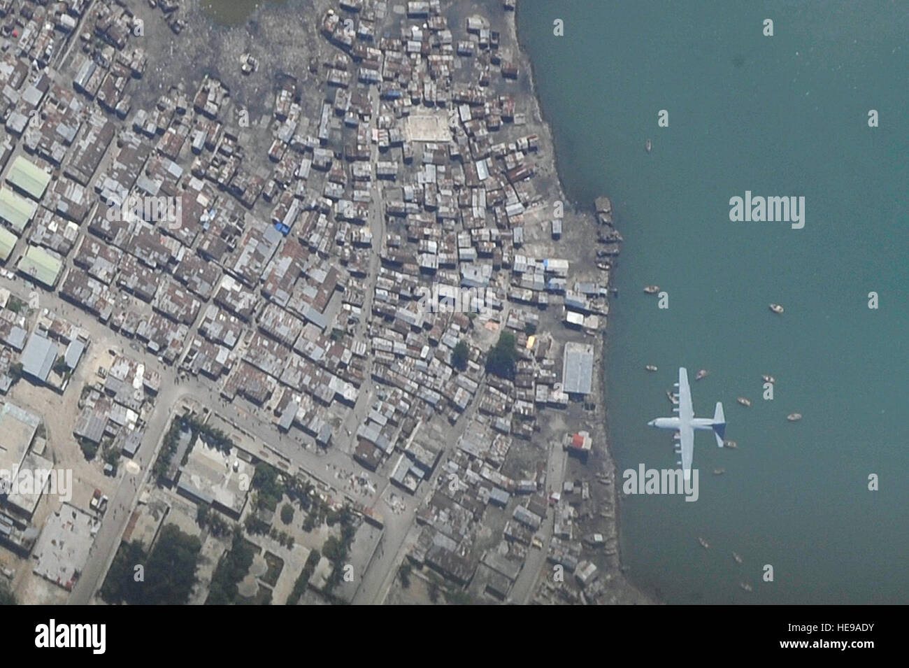 Eine c-130 Hercules-Flugzeuge macht einen Endanflug in internationalen Flughafen Toussaint Louverture in Port-au-Prince, Haiti, 16. Januar 2010. Aus einer Höhe von 15.000 Fuß, ein US-Air Force OC-135B Open Skies Beobachtung Flugzeug nutzt 10.000 Fuß des Films zu fotografieren, die Verwüstung durch ein 7,0 Erdbeben sowie Hilfsmaßnahmen, die auf dem Gebiet.  Airman 1st Class Perry Aston Stockfoto