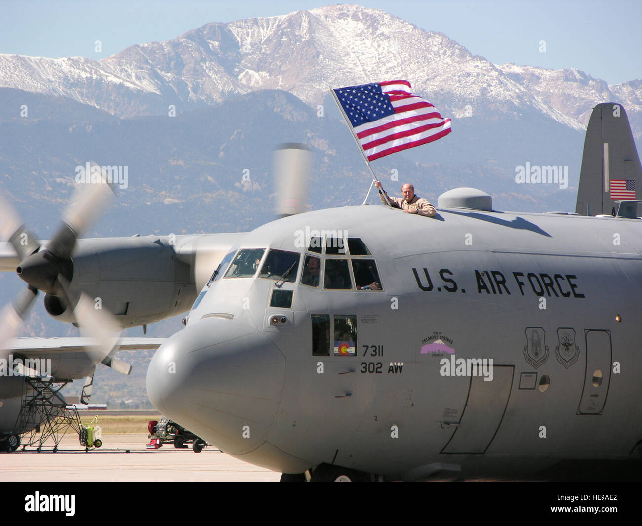 PETERSON AIR FORCE BASE, Colorado (AFRC)--Major Stephen Stelly, 731st Luftbrücke Flug Staffelkapitän, zeigt stolz die amerikanische Flagge als eine 302. Airlift Wing c-130 vorbei an Pikes Peak während der jüngsten Heimkehr taxis. Flügel Mitglieder endete am 4. Okt. 14 Monaten Einsätze zur Unterstützung der US Central Command Einsätze in Südwestasien.  Master Sergeant Mark Clark) Stockfoto