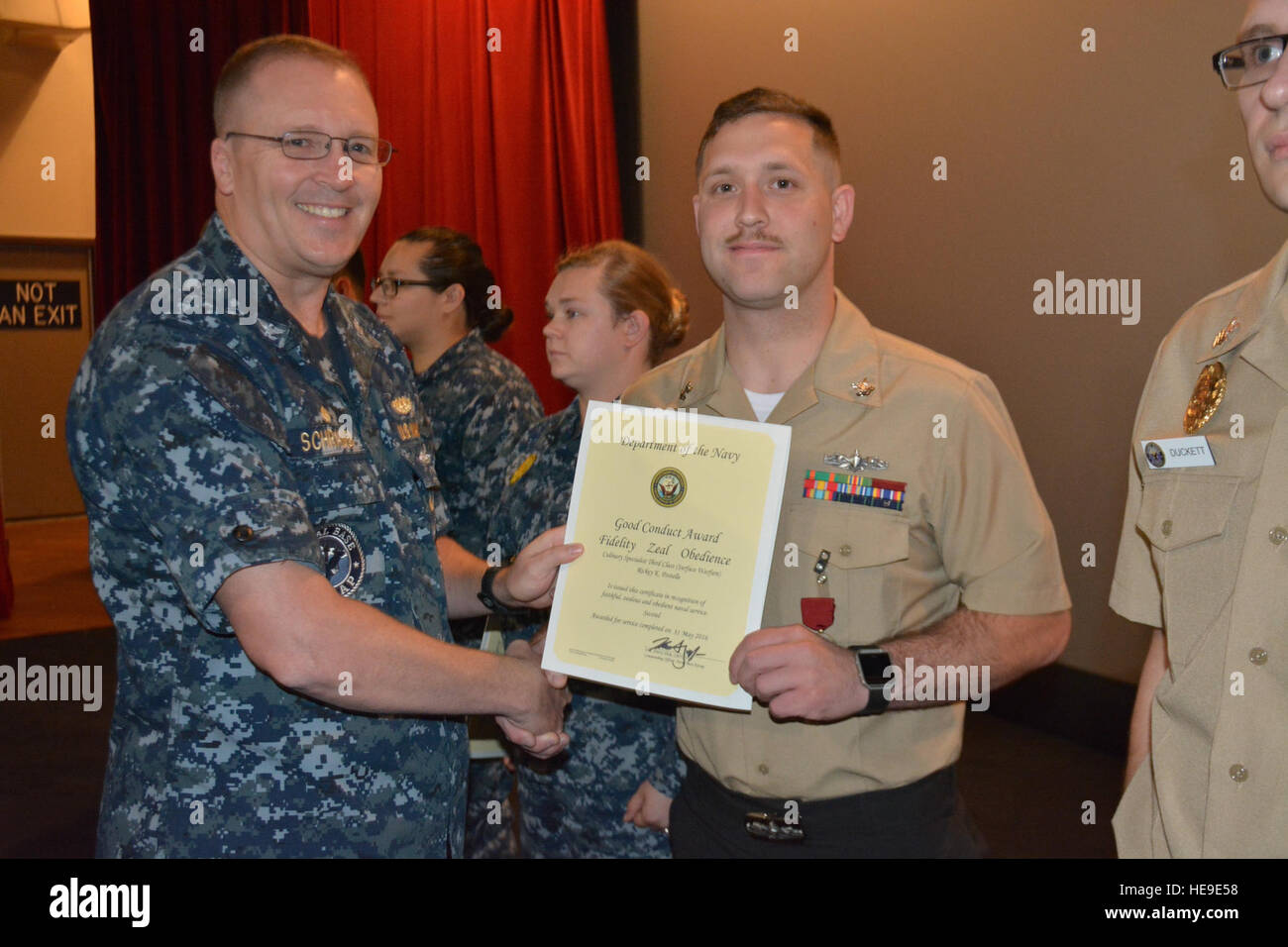 160921-N-VM861-012 BANGOR, Washington (21. September 2016) - Captain Alan Schrader, Naval Base Kitsap (NBK) Kommandierender Offizier, präsentiert kulinarische Spezialist 2. Klasse Rickey Postelle mit einer guten Conduct Medaille während eines Anrufs alle Hände an die NBK-Bangor Plus Kino statt. Mehr als 30 Auszeichnungen und Dekorationen wurden zu den Seeleuten während der Anlass verliehen. Es war Schraders ersten All-Hallen als NBK CO nennen.  Petty Officer 3. Klasse Jessica Maue) Stockfoto