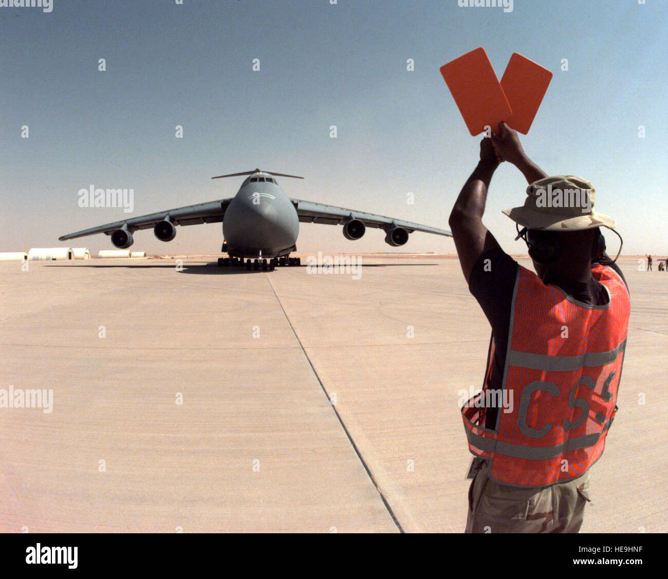 960807-F-2829R-004 Staff Sgt. James Larose Marschälle eine US Luftwaffe C-5 b Galaxy zu einem Parkplatz auf der Rampe auf Prince Sultan Air Base in Al Kharj, Saudi-Arabien, am 7. August 1996.  Die Galaxie bringt Ingenieure, Ausrüstungen und Zubehör, eine Zeltstadt zu Haus US-Soldaten, die Durchführung der Operation Southern Watch zu konstruieren.  Fast 4.000 Mitarbeiter, Flugzeuge und Ausrüstung sind von Stützpunkten in Dhahran und Riad in der abgelegenen Wüste Air Base verschoben, ihre Anfälligkeit für Terroranschlag zu reduzieren.  Southern Watch ist die USA und Koalition Durchsetzung der keine-Fly-Zone über südlichen ich Stockfoto