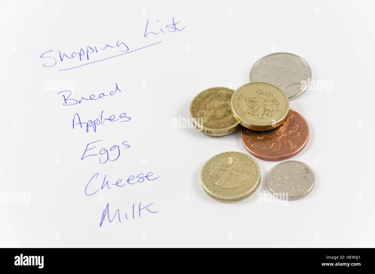 Eine Einkaufsliste und eine Handvoll Münzen zum bezahlen der Elemente in der Liste. Stockfoto