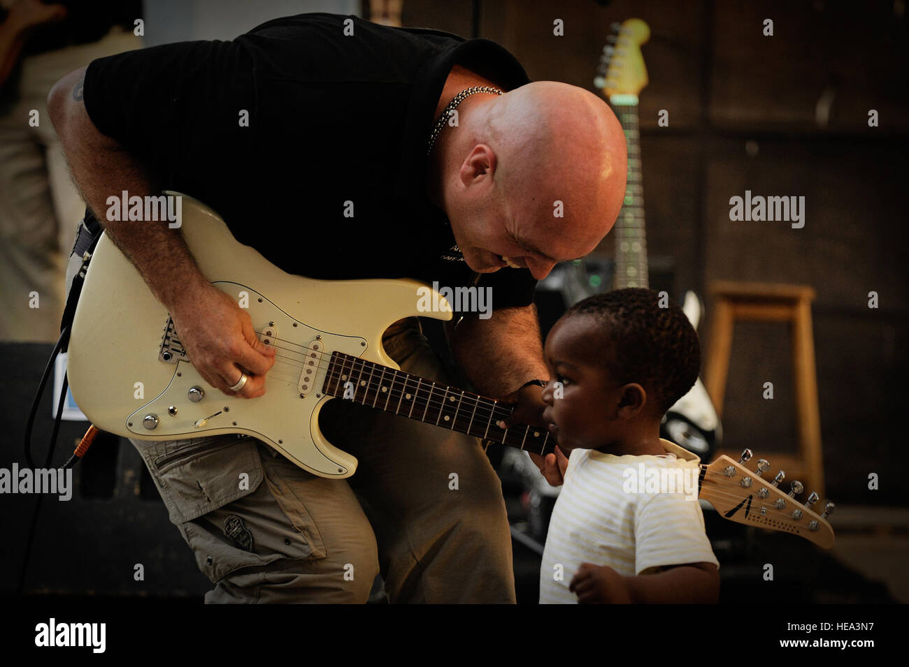 Techn. Sgt Jason Cale, US Air Forces in Europa und Afrika Air Forces Gitarrist der Band bietet ein Kind eine Chance, seine Gitarre während eines Konzerts in Dakar, Senegal, 14. Juni 2014, an einem lokalen kulturellen Zentrum zu spielen. USAFE-AFAFRICA Flieger sind im Senegal für afrikanische Partnerschaft Flug, ein Programm zur Verbesserung der Kommunikation und Interoperabilität zwischen regionalen Partnern in Afrika. Die Band spielt mehrere Locations in der Umgebung, Kindern und Musikern durch die universelle Sprache der Musik zu begeistern.  Staff Sgt. Ryan Crane) Stockfoto