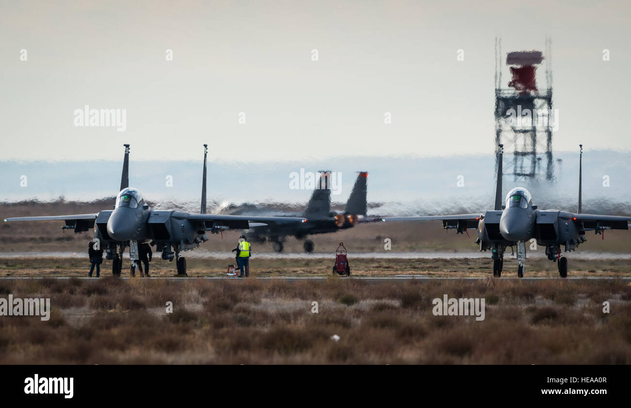 Wartungsteams führen letzten preflight Checklisten auf Republic of Singapore Air Force F-15SGs, während ein US Air Force F-15E Strike Eagle dahinter in Mountain Home Air Force Base, Idaho, 16. Oktober 2013 startet. Der Flug war Teil des Berges Roundup, eine massive Multi-service, multi-nationalen Bewegung.  Techn. Sgt. Samuel Morse Stockfoto