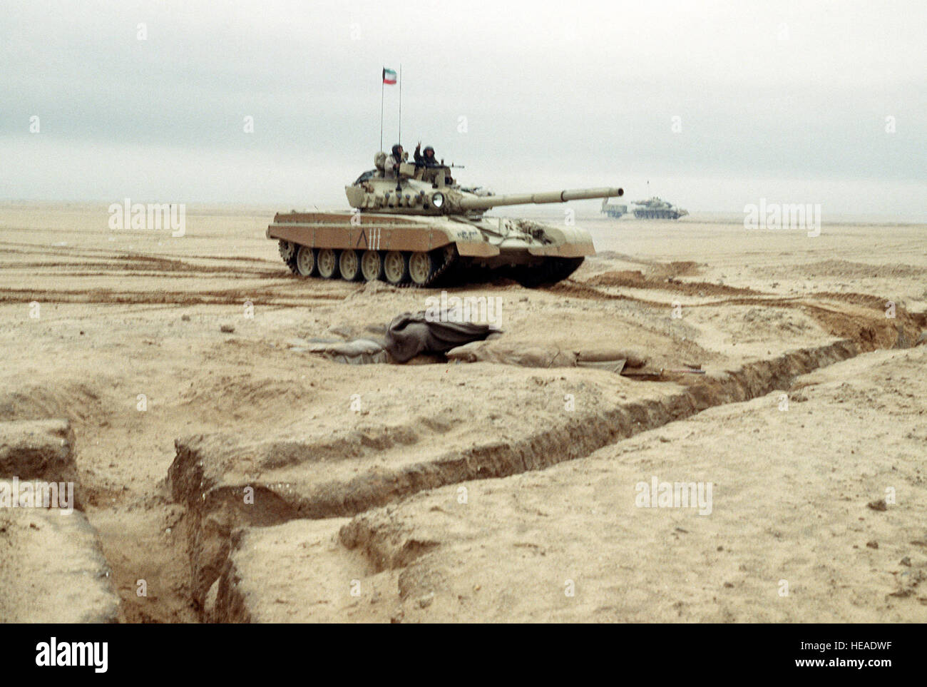 Kuwaitischer Flagge fliegt von einem Kampfpanzer t-72 als ein Soldat gibt ein Victory-Zeichen wie der Tank entlang eines Kanals von Minen geräumt werden, während der Operation Desert Storm angetrieben werden. Stockfoto