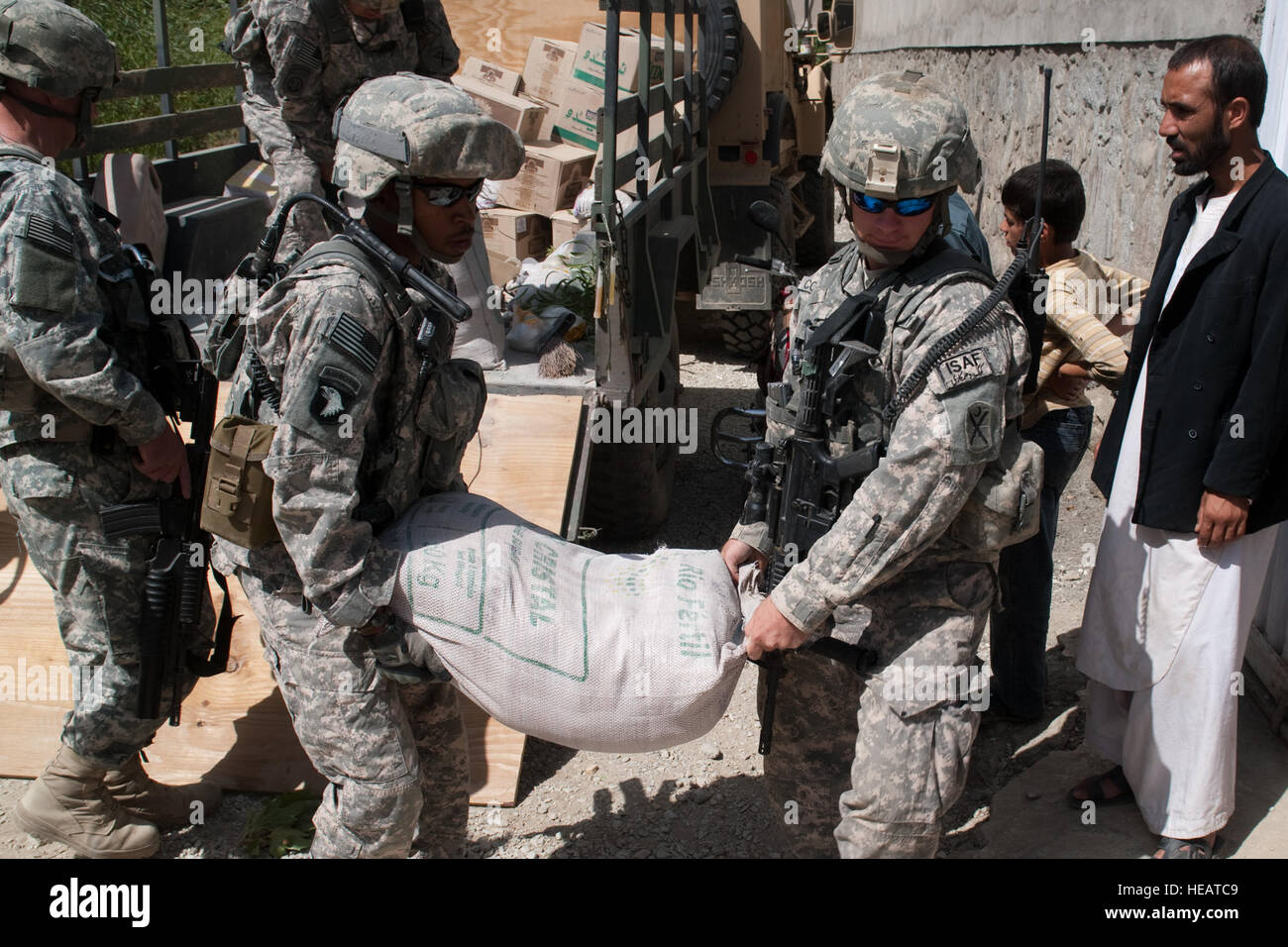 KAPISA Provinz, AFGHANISTAN--US Army Spc. Michael Bell und CPL. Kevin Coleman mit provinzielle Rekonstruktion Team Kapisa entladen 110 Pfund Taschen von Lebensmitteln an der medizinischen Klinik in Nijrab Dorf am 1. August 2010. Das Essen ist Teil des Programms stark Lebensmittel, die kalorienreichen Ernährung für afghanische Kinder während ihrer primären Entwicklungsjahre bereitstellt. Das FHM-Mission ist zur Stabilisierung der Region durch die Aktivierung der lokaler Regierungen, pflegen, erziehen, beschäftigen und schützen ihres Volkes durch den Aufbau der Basisinfrastruktur und Mentoring.  Techn. Sgt. Joe Gesetze, USAF / veröffentlicht) Stockfoto