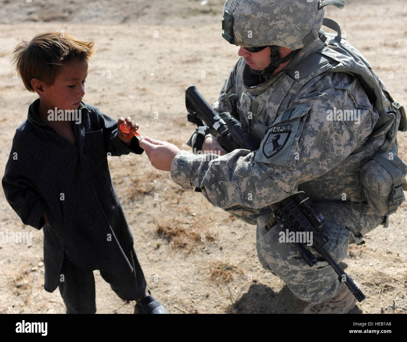 Provinz GHAZNI, Afghanistan – US Armee Sgt. Brian Dalka, Sicherheit Kraft Mitglied mit Ghazni Provincial Reconstruction Team, verleiht Süßigkeiten ein Lokalmatador aus einem "Rückkehrer" Dorf außerhalb der Stadt Ghazni, Afghanistan, Dez. 3. Ghazni PRT war in dem Dorf, auf einem abgeschlossenen Projekt von US Agency for International Development finanziert zu überprüfen. Das Gebäude wurde mit Hilfe eines Zuschusses von USAID gebaut und wird von den rund 750 Dorfbewohnern als Gemeindezentrum verwendet. Die Menschen in diesem Dorf wurden ursprünglich aus der Dichondi Provinz aber flohen in den 90er Jahren nach dem Bürgerkrieg und Dürre pla Stockfoto