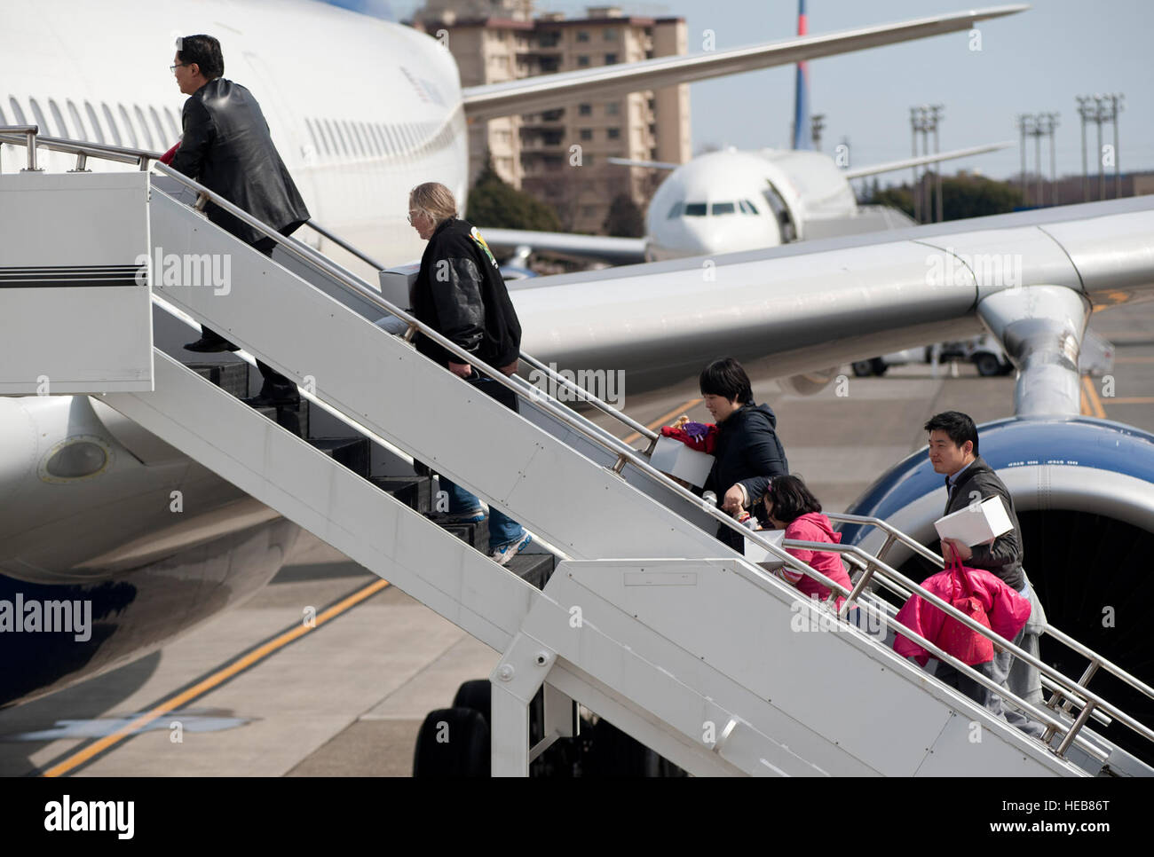 Passagiere steigen in Flugzeuge der Delta Airlines auf der Yokota Air Base in Japan ein, nachdem sie vom Flughafen Narita aufgrund eines Erdbebens der Stärke 8,9 vor der japanischen Ostküste umgelenkt wurden, was einen sicheren Transport und eine kontinuierliche Betriebsführung sicherstellte. Stockfoto