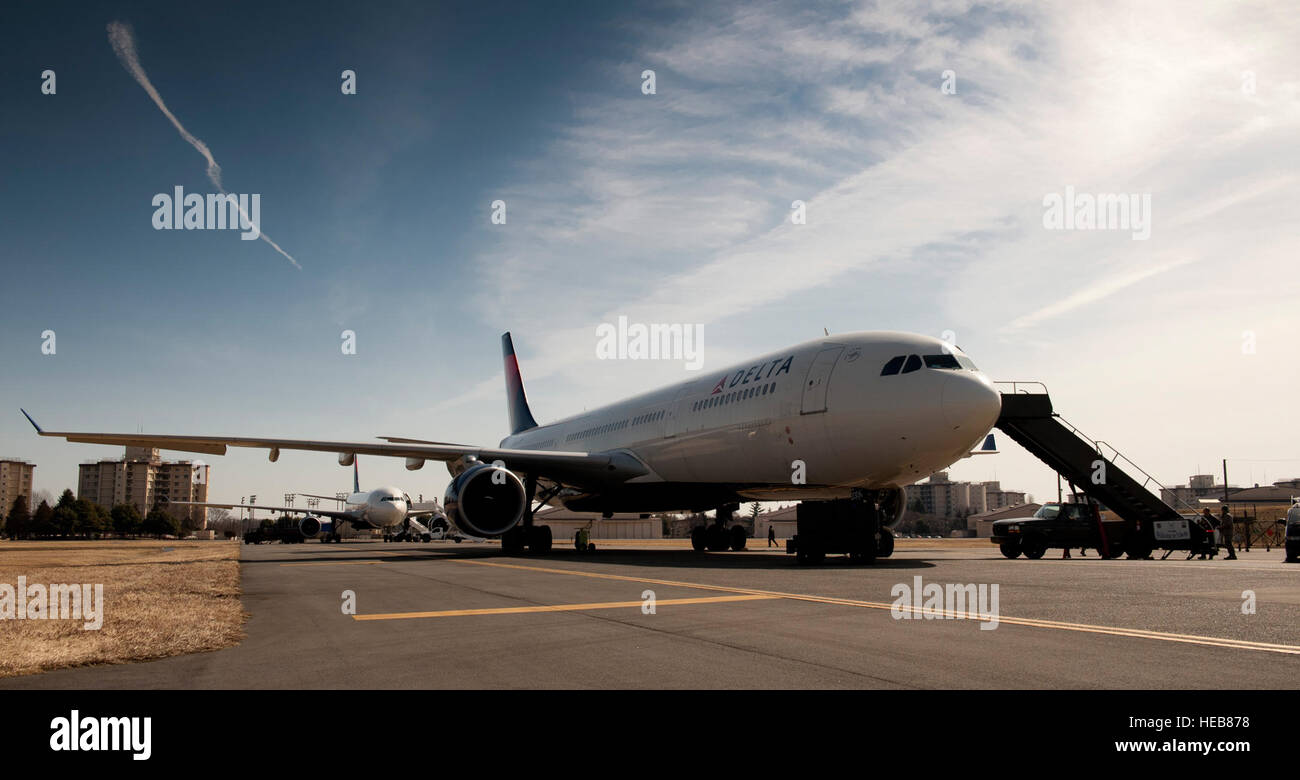 Flugzeuge bereiten am 12. März 2011 zwei Delta-Airlines-Flugzeuge für den Einstieg auf der Yokota Air Base in Japan vor, nachdem sie aufgrund eines Erdbebens der Stärke 8,9 vor Japans Ostküste umgelenkt wurden und die Notfalleinsätze unterstützen. Stockfoto