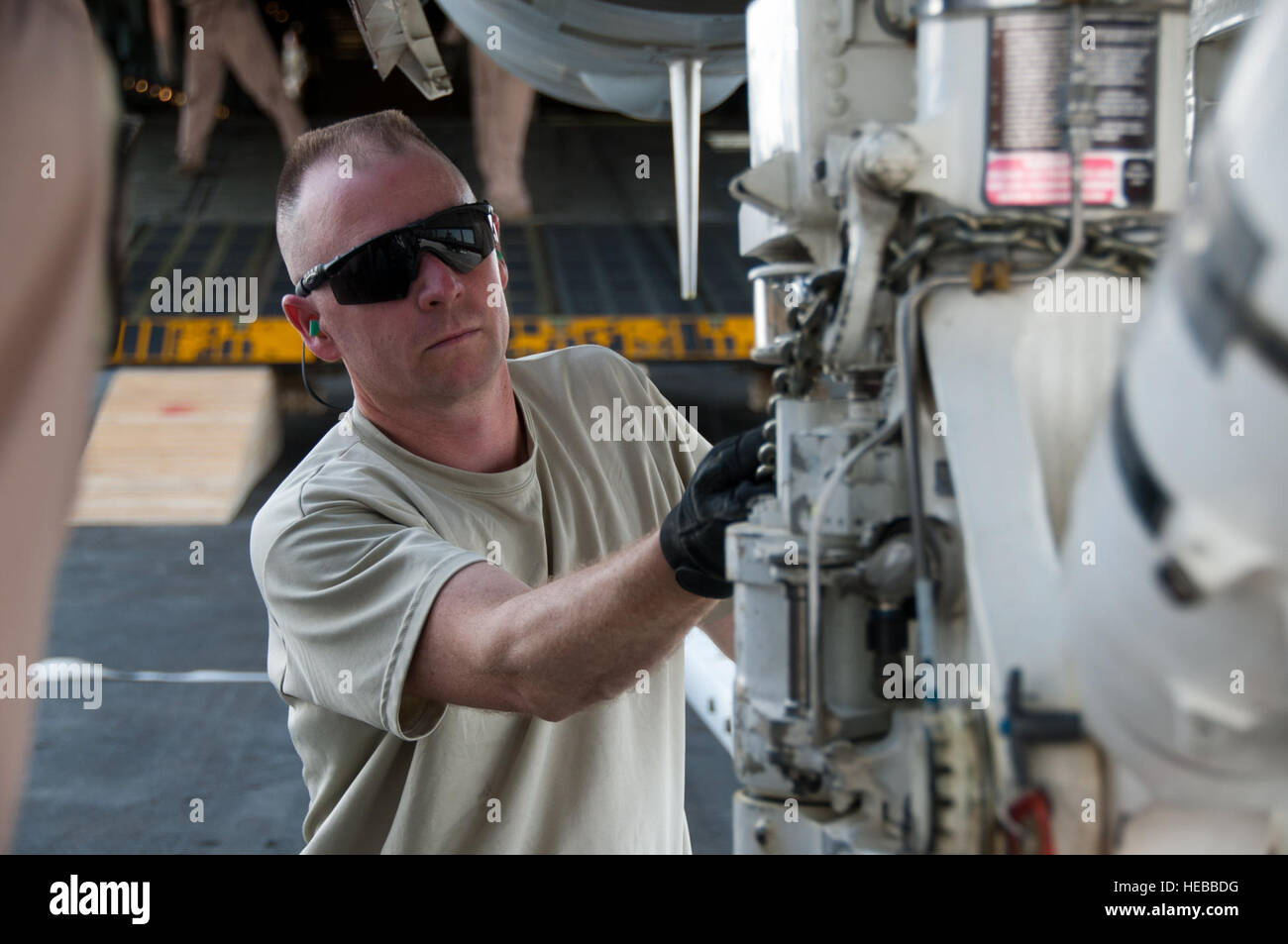 Master Sergeant Raymond Sambor, 451st Expeditionary Logistik Bereitschaft Squadron Antenne Port Offizier vom Dienst, legt eine laden-Kette auf ein F/118 Super Hornet am Kandahar Flugplatz, Afghanistan, 18. August 2011. Sambor und mehrere Mitglieder der 451st ELRS Antenne Port unterstützt die Last von einer F/A-18 Super Hornet auf einer c-5 Galaxy. Dies war das erste Mal überhaupt, das ein US-Kampfjet in ein Frachtflugzeug für den Transport zurück in die Vereinigten Staaten geladen wurde. Nach Monaten der Koordination und Planung, senior Führungskräfte bei der Navy Naval Air Forces und der Air Force Air Mobility Command genehmigt eine Stockfoto