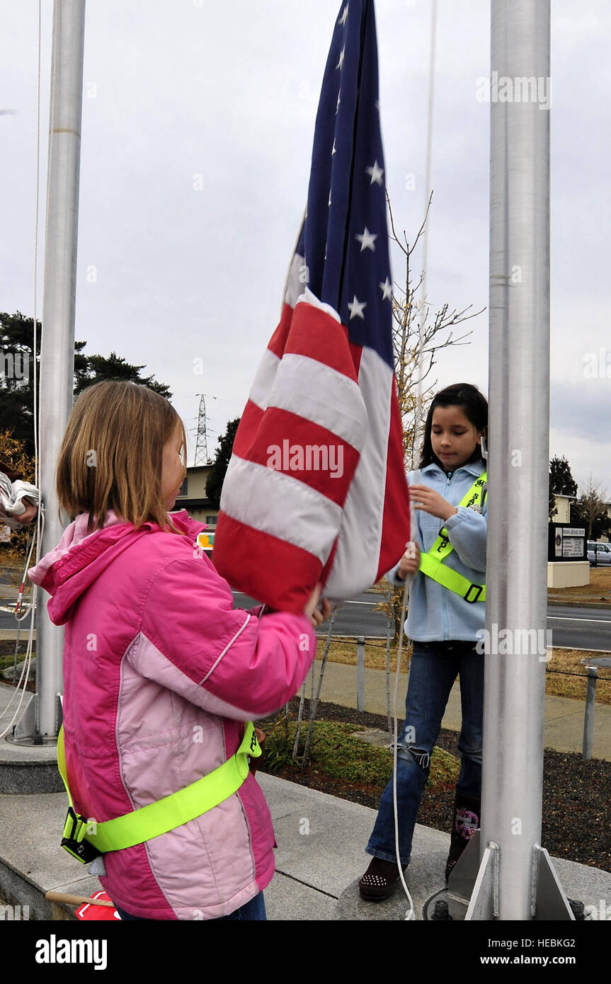 Samantha Browning, rechts, und Hailey Fredrick, beide 10 Jahre alt, erhöhen die amerikanische Flagge in Sollars Elementary School, März 21. Base Schulen sind zurück in Session mit allen Buslinien laufen und Klassen zu den normalen Zeiten beginnen. Die Schulen wurden geschlossen, eine Woche nach macht durch ein Erdbeben, das die nördliche Küste von Japan 11 März erschütterte, ausgeschlagen war. Stockfoto