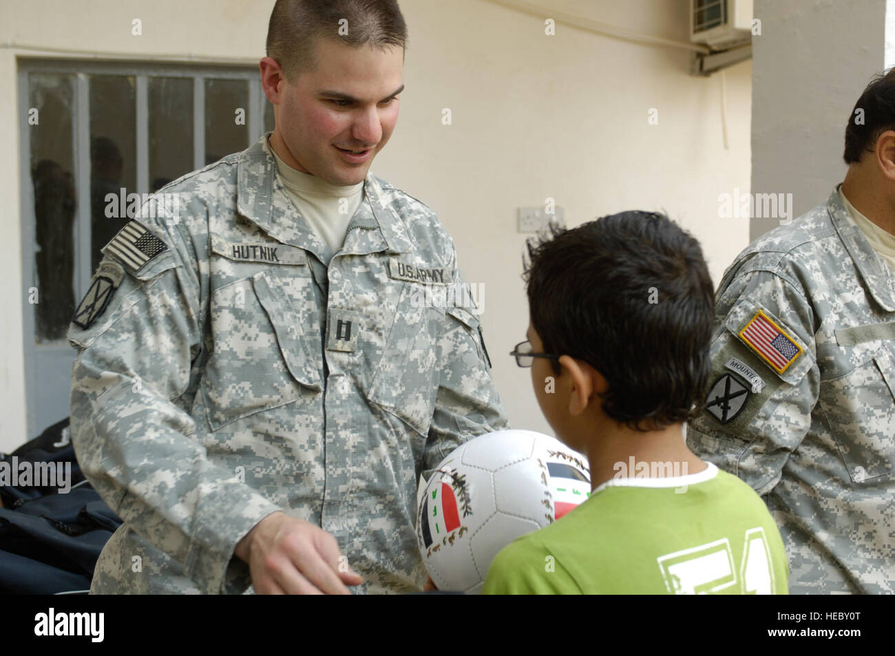 US Armee-Kapitän Stefan Hutnik, Commander, Alpha-Batterie, 3. Bataillon, 6. Feldartillerie, 10th Mountain Division, Fort-Trommel, N.Y., bereitgestellt auf Forward Operating Krieger, Kirkuk, Hände einen Fußball, ein leistungsstärksten Schüler von Altun Kapri im Rat Stadt bauen, 20. August 2008. Stockfoto