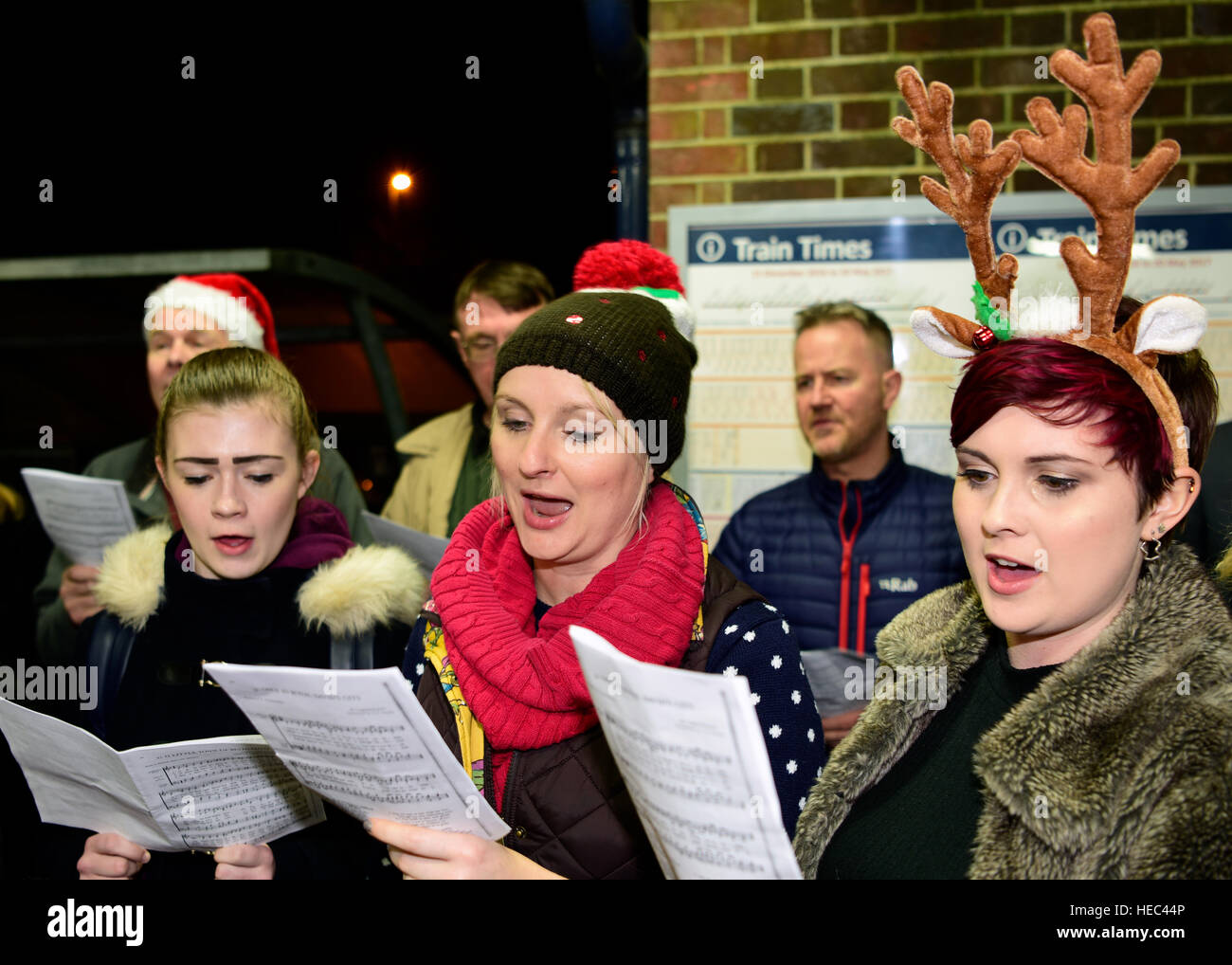 Marie Curie Cancer Charity Freiwilligen singen Weihnachtslieder in einem Zug station Plattform, Farnham, Surrey, UK. Stockfoto