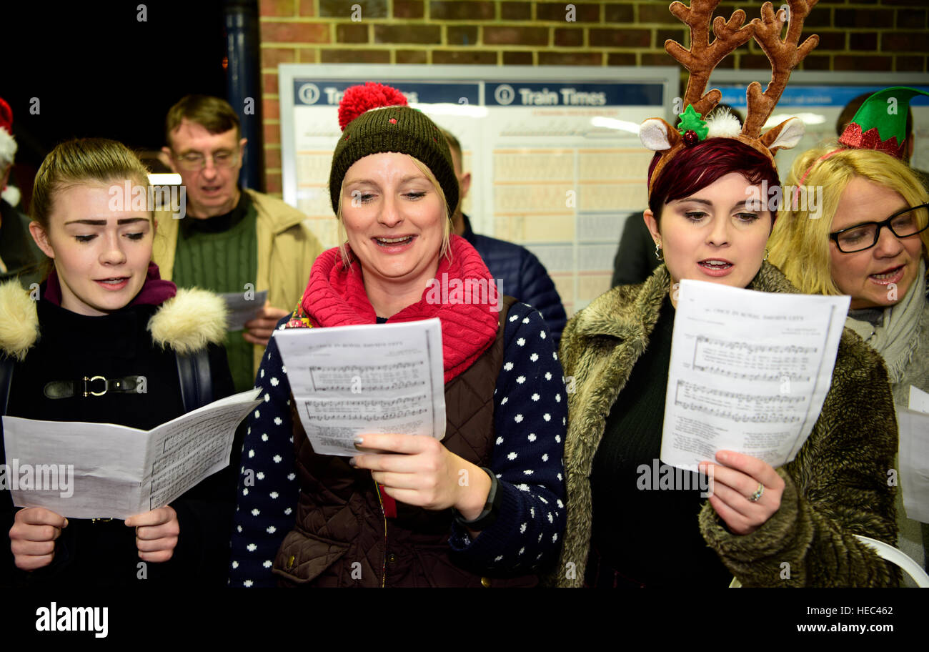 Marie Curie Cancer Charity Freiwilligen singen Weihnachtslieder in einem Zug station Plattform, Farnham, Surrey, UK. Stockfoto