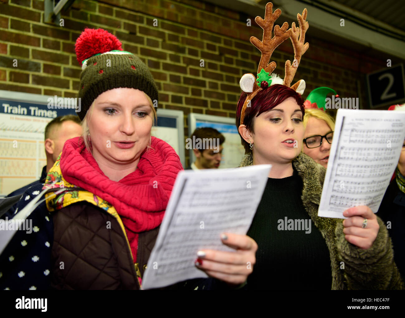 Marie Curie Cancer Charity Freiwilligen singen Weihnachtslieder in einem Zug station Plattform, Farnham, Surrey, UK. Stockfoto