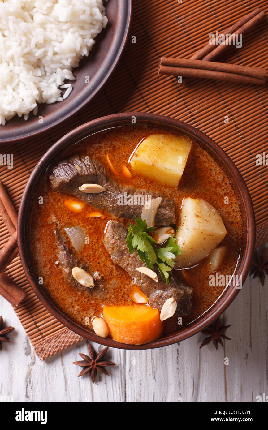 Heißen traditionelle Thai Rindfleisch Massaman Curry mit Erdnüssen und Reis Beilage hautnah. vertikale Ansicht von oben Stockfoto