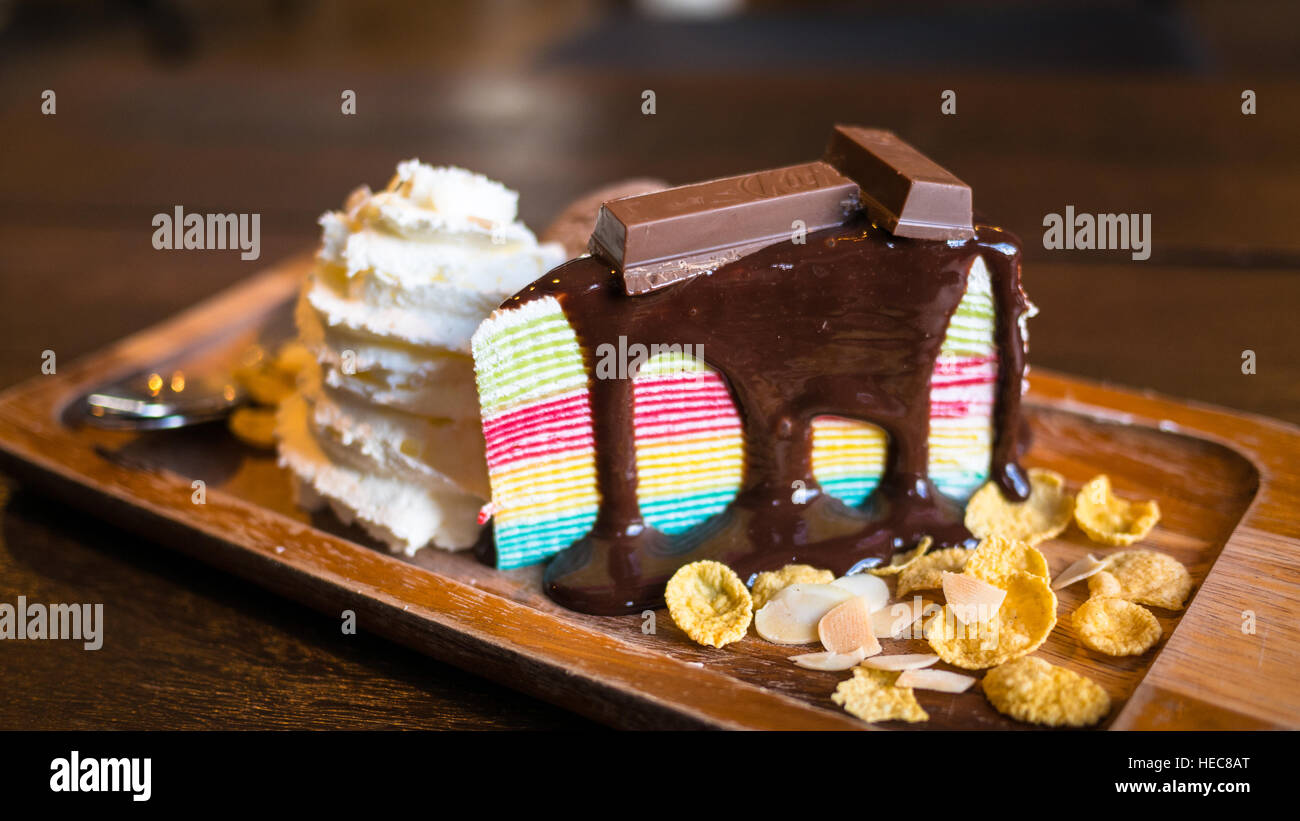 Regenbogen Krepp Kuchen mit Creme abwischen und Dekoration auf weißen Teller. (Tiefenschärfe) Stockfoto