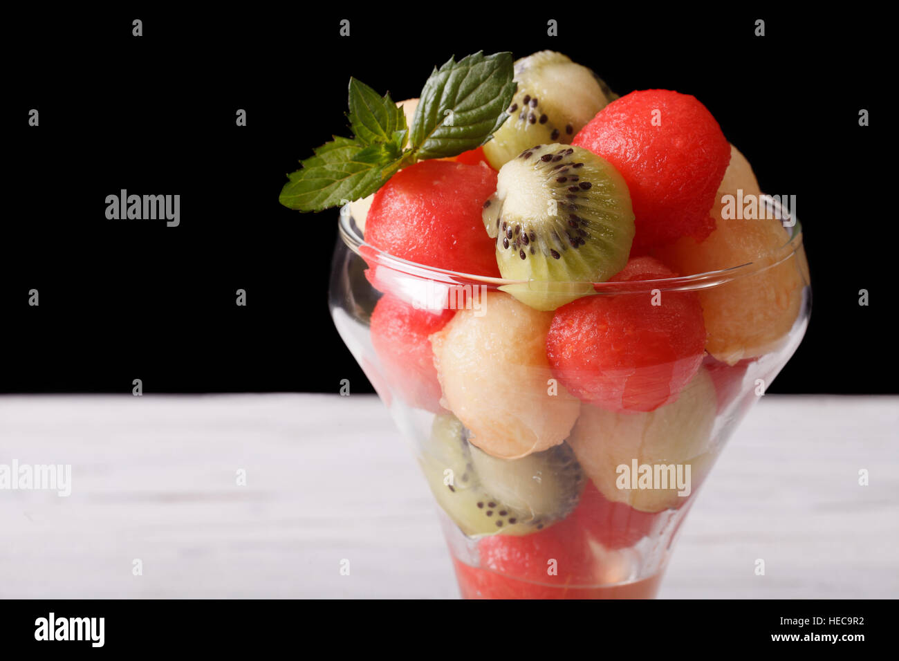 Obstsalat mit Wassermelone, Kiwi und Melonen in einer Glas-Nahaufnahme. horizontal auf einem dunklen Hintergrund Stockfoto