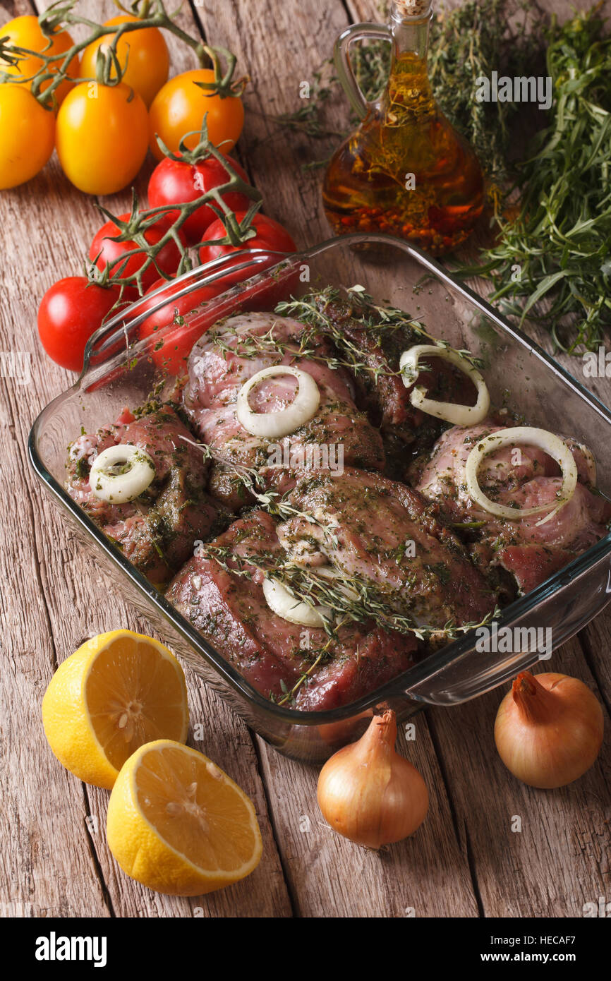 Grill rohes Fleisch mit Zwiebeln, Kräutern und Zitrone mariniert hautnah in eine Schüssel geben und die Zutaten auf den Tisch. vertikale Stockfoto