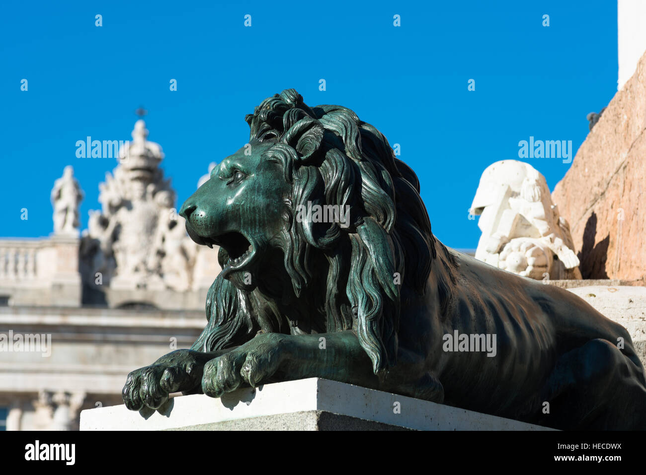 Madrid, Spanien. Eines der Bronze Löwen am Plaza de Oriente mit Palacio Real oder Königspalast Hintergrund. Stockfoto