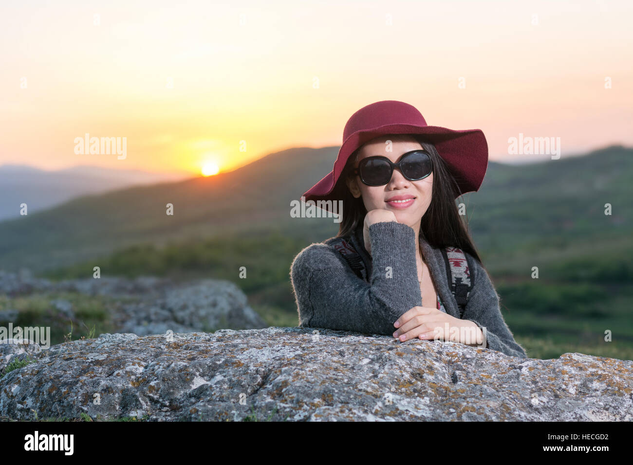 Weibliche Wanderer Sonnenuntergang auf einem Felsen sitzend Stockfoto