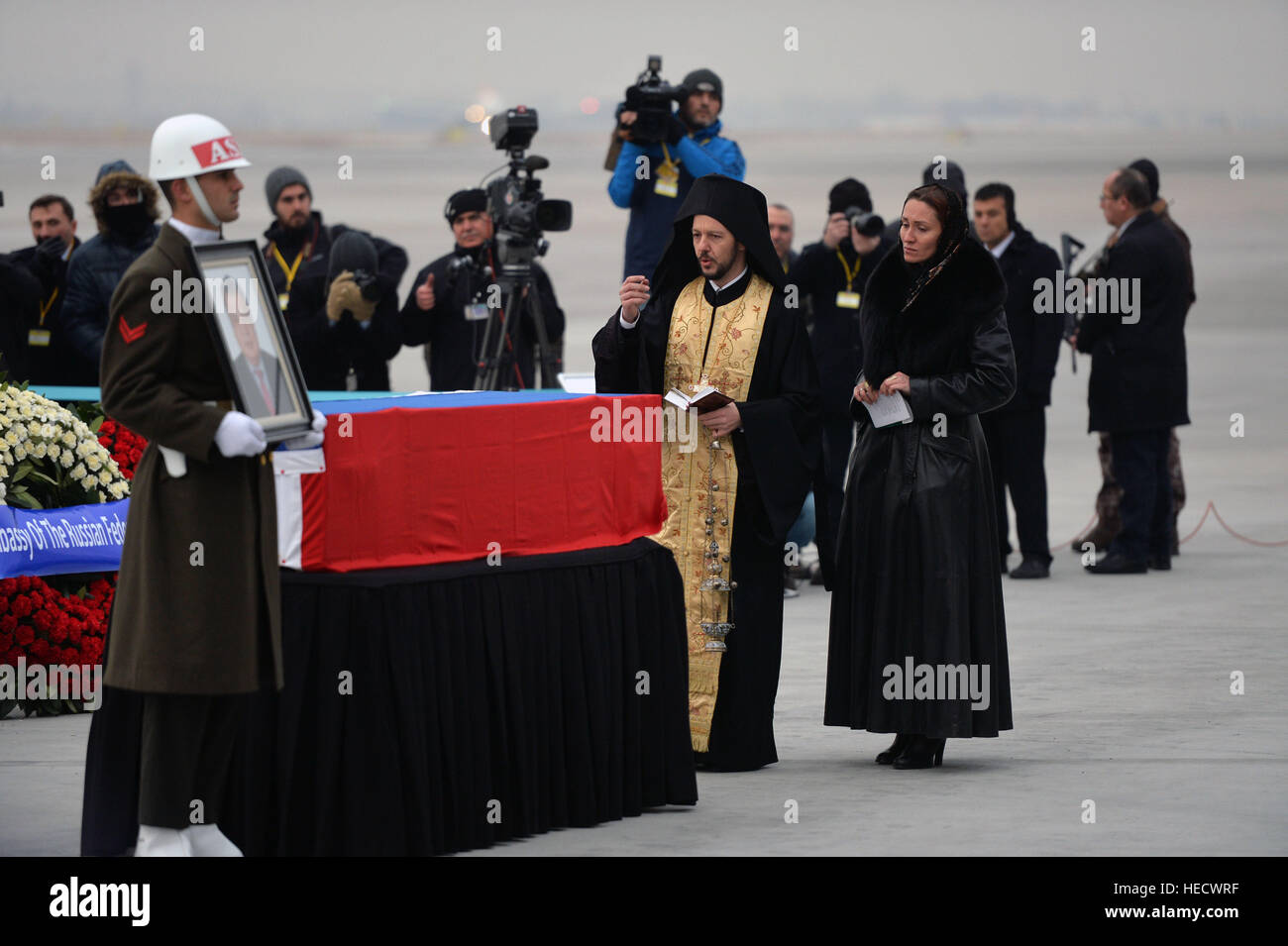 Ankara, Türkei. 20. Dezember 2016. Ein orthodoxer Geistlicher betet weiter, um die Flagge gehüllt Sarg des späten russischen Botschafter in der Türkei Andrei aus während einer Zeremonie am Flughafen Ankara-Esenboğa in Ankara, Türkei, 20. Dezember 2016, bevor der Sarg auf ein russisches Flugzeug nach Moskau transportiert wird. © Mustafa Kaya/Xinhua/Alamy Live-Nachrichten Stockfoto