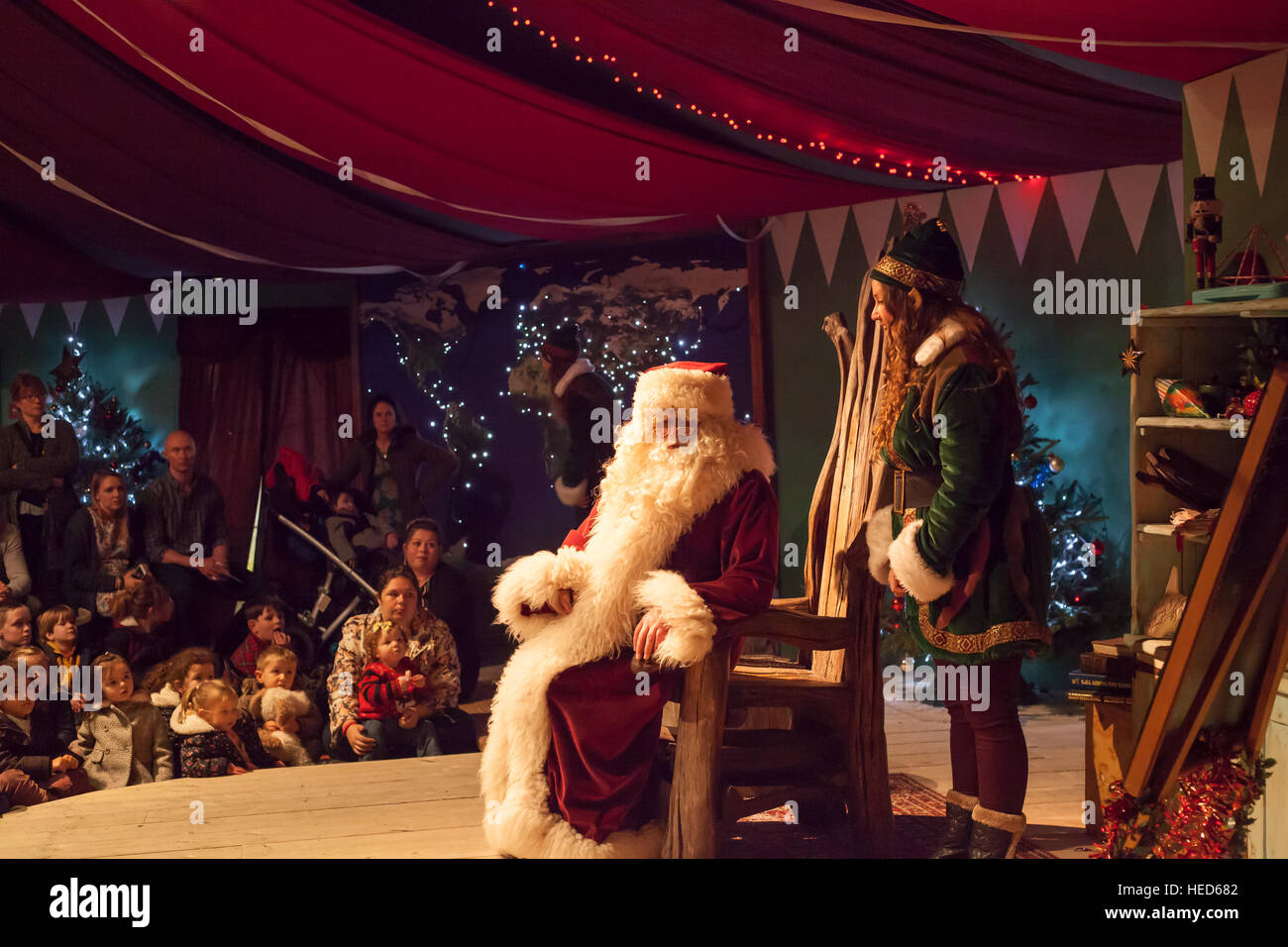 Weihnachtsmann, auch bekannt als Santa Claus unterhaltsame Kinder und Eltern mit Elfen und Helfer. Festliche Szene. Stockfoto