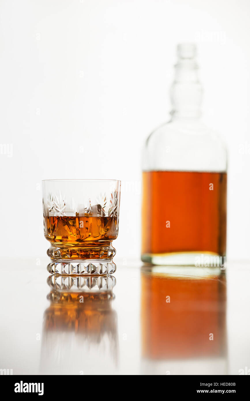Whiskeyglas mit Flasche auf weißem Hintergrund. Stockfoto