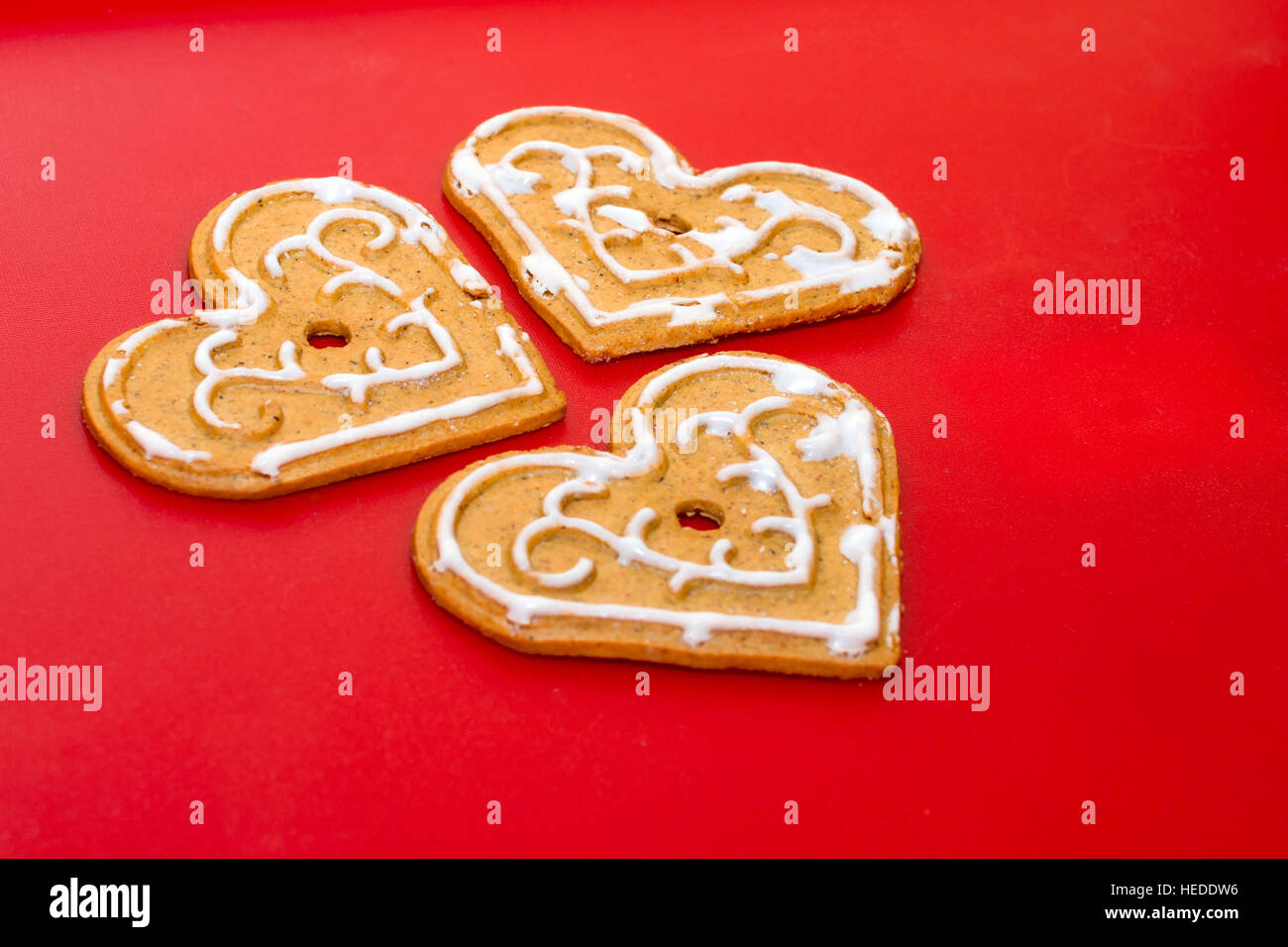 Cookies in Form von Herzen zum Valentinstag auf auf Hintergrund rot Matt Kunststoff. Festliche Leckerbissen für Liebhaber zu feiern. Urlaub-Lebkuchen Stockfoto