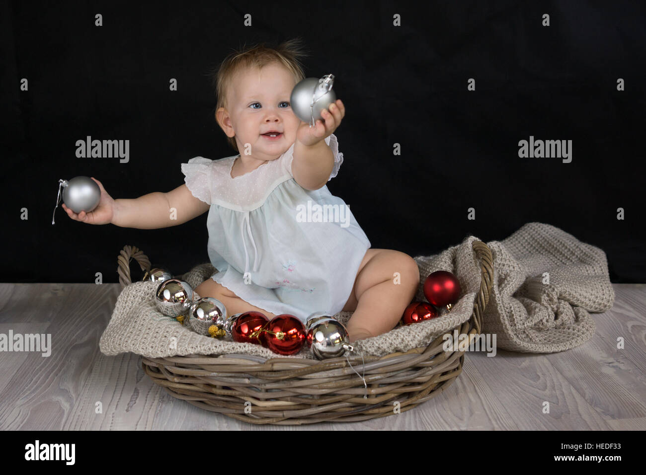 Babymädchen halten und spielen mit Weihnachtskugeln Stockfoto