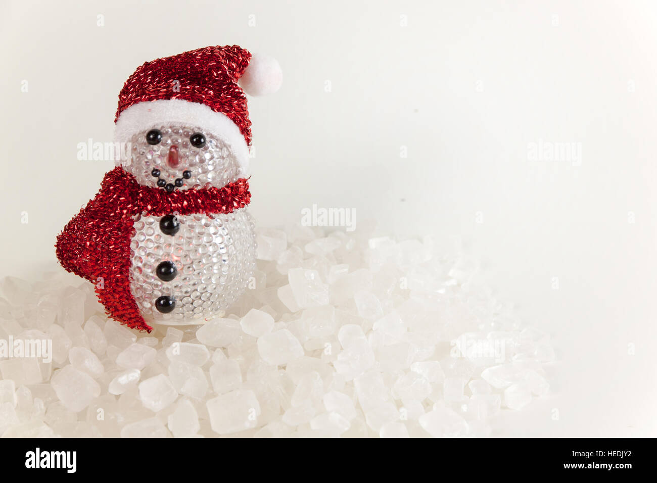 Schneemann auf einem Stapel von weißen kristallinen mit weißem Hintergrund. Stockfoto
