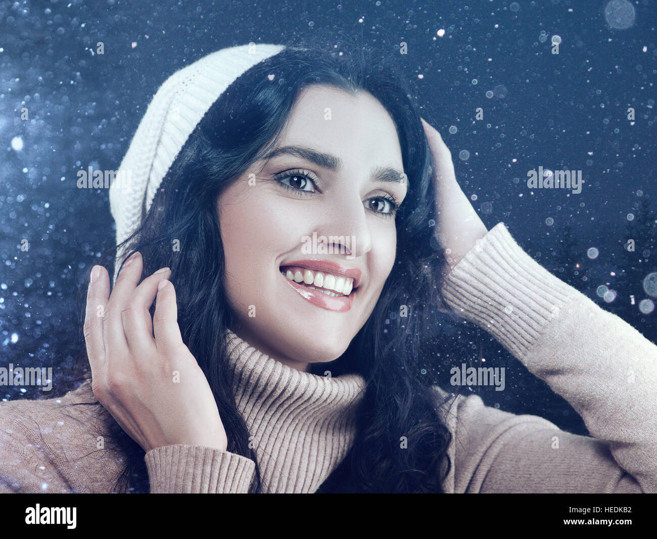 Weiße Schönheit Frau Wintermütze und Pullover bekleidet posiert Agaist Schneefall Stockfoto