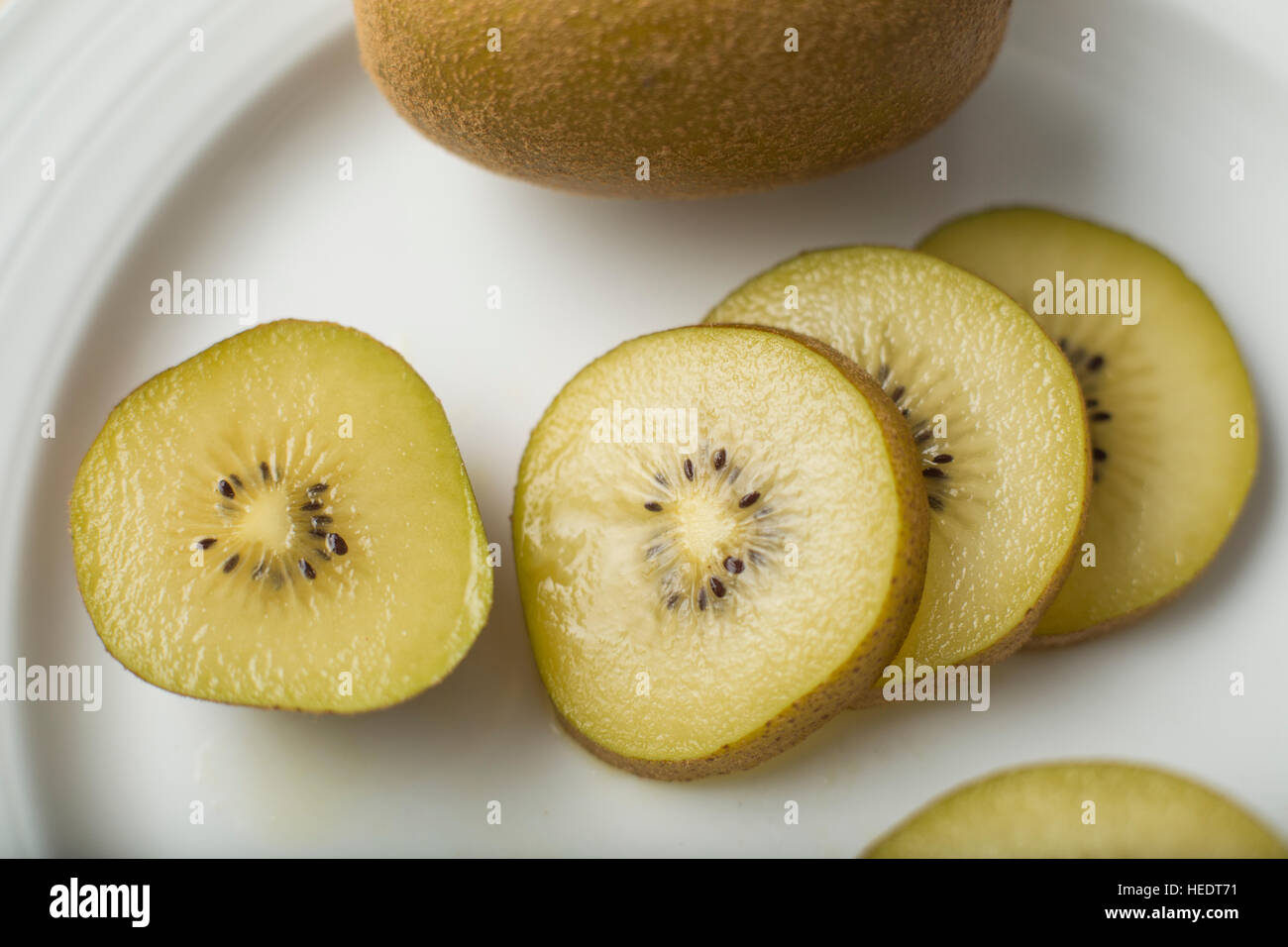 Nahaufnahme eines geschnittenen goldenen Kiwis auf einem weißen Teller Stockfoto