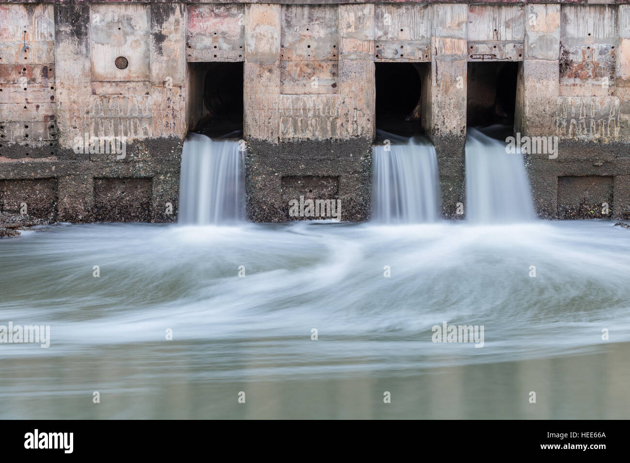 Wasser fließt aus Abfluss zum Fluss Stockfoto