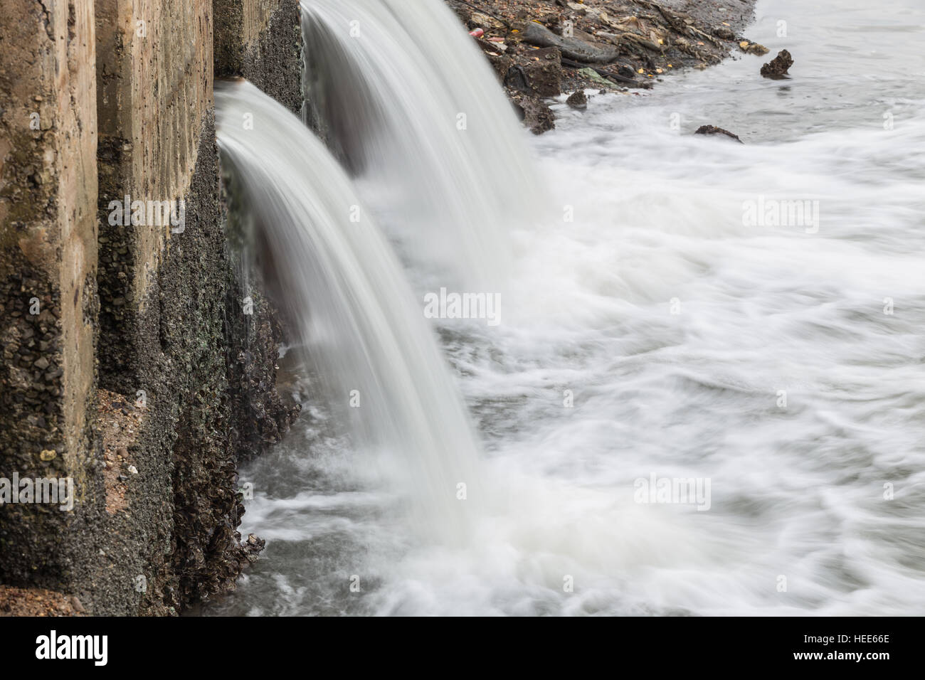 Wasser fließt aus Abfluss zum Fluss Stockfoto