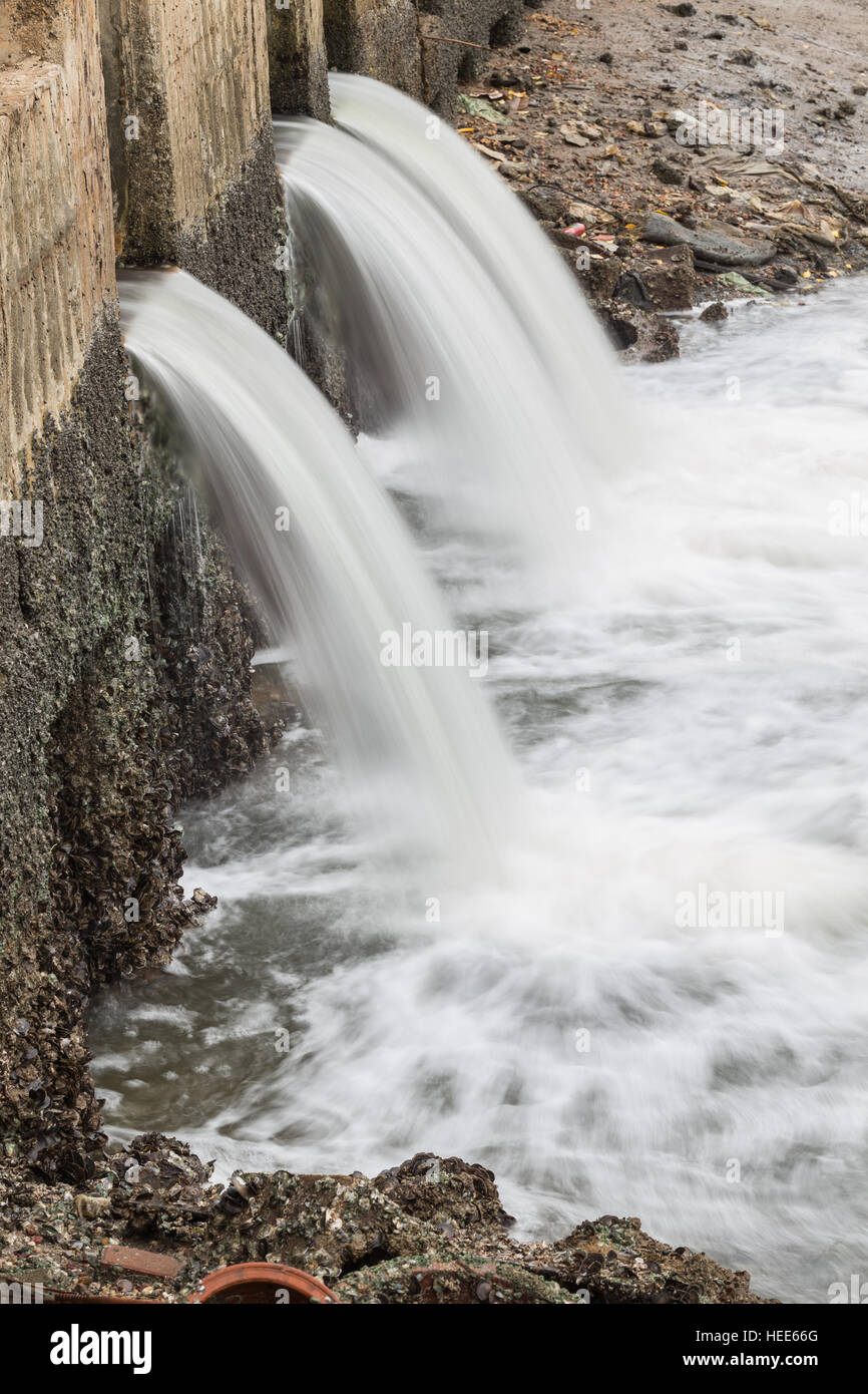 Wasser fließt aus Abfluss zum Fluss Stockfoto