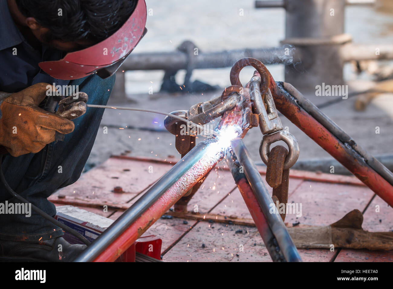 Ein Mann Schweißen Stahl seitens Fischerboot am Hafen Stockfoto