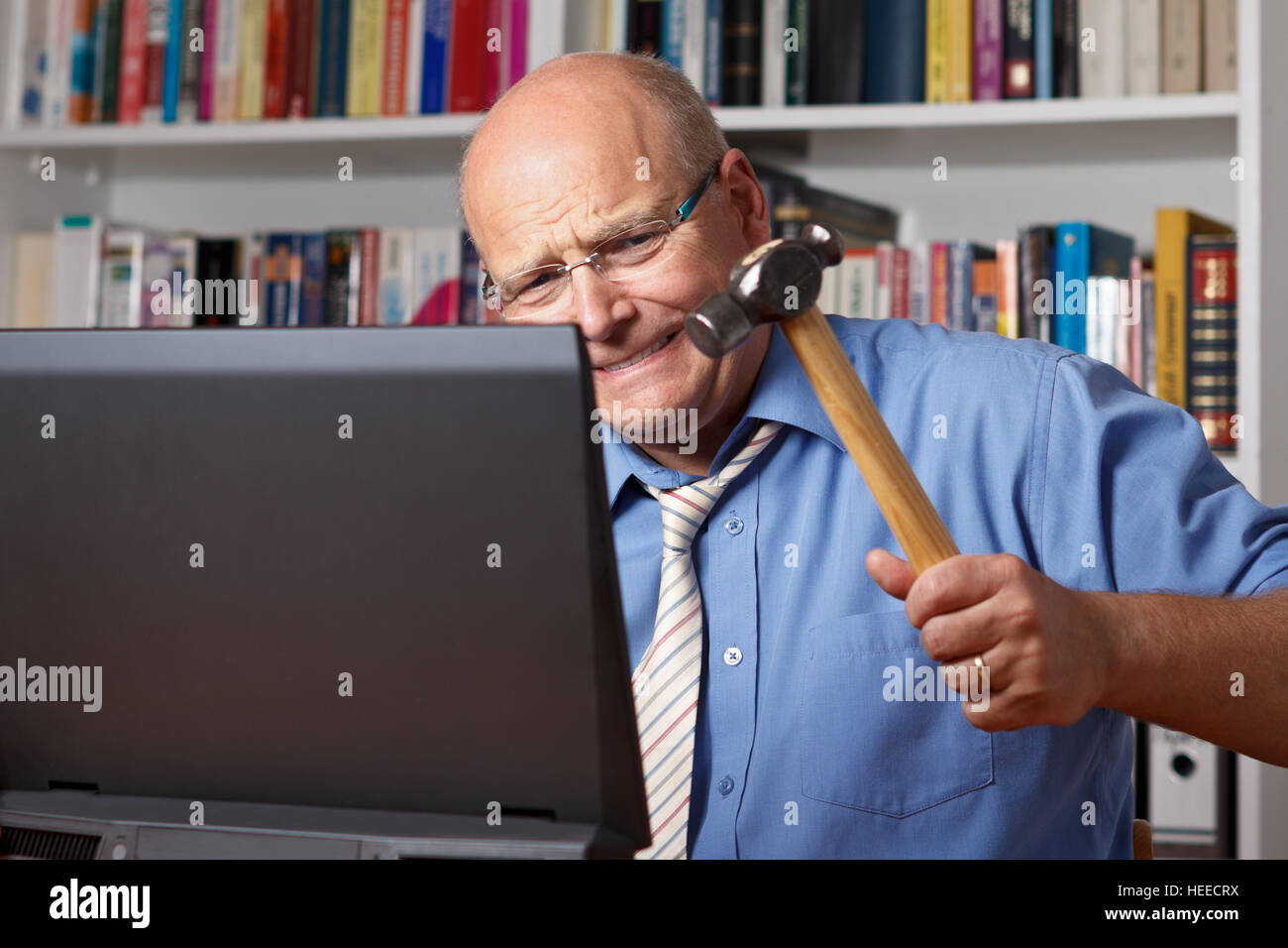 Sehr böse alte Mann mit Hemd und Krawatte auf seinen Computer mit einem Hammer, Frust, Stress, Krise Stockfoto