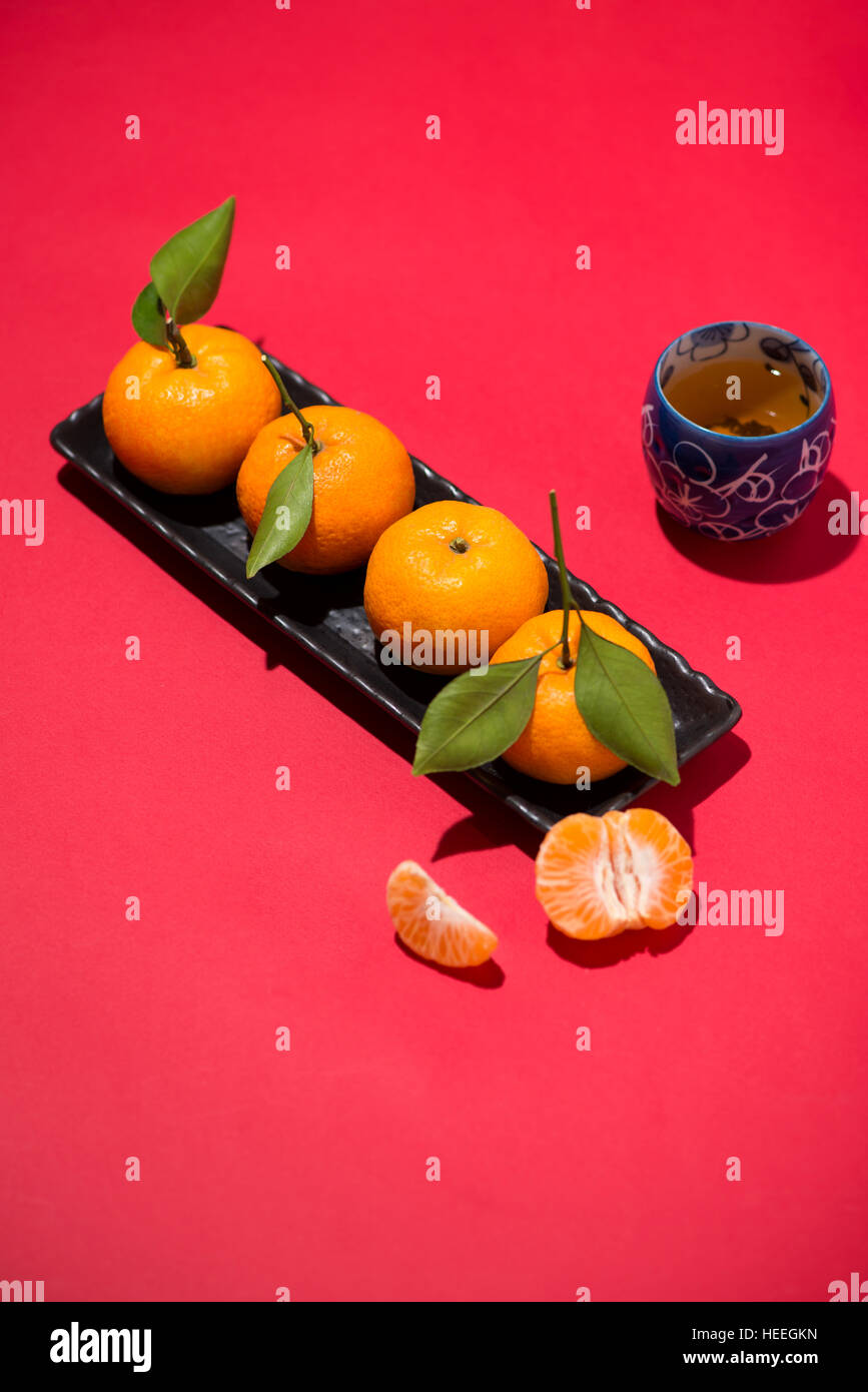 Chinesisches Neujahrsfest mit Mandarine und Tee auf rotem Grund Stockfoto