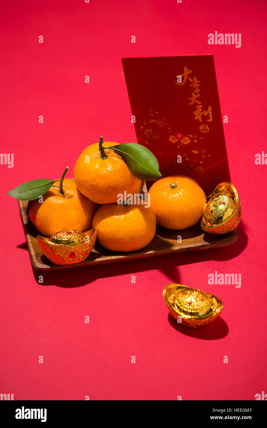 Chinesisches Neujahrsfest. Mandarine mit Umschlag auf rotem Grund Stockfoto