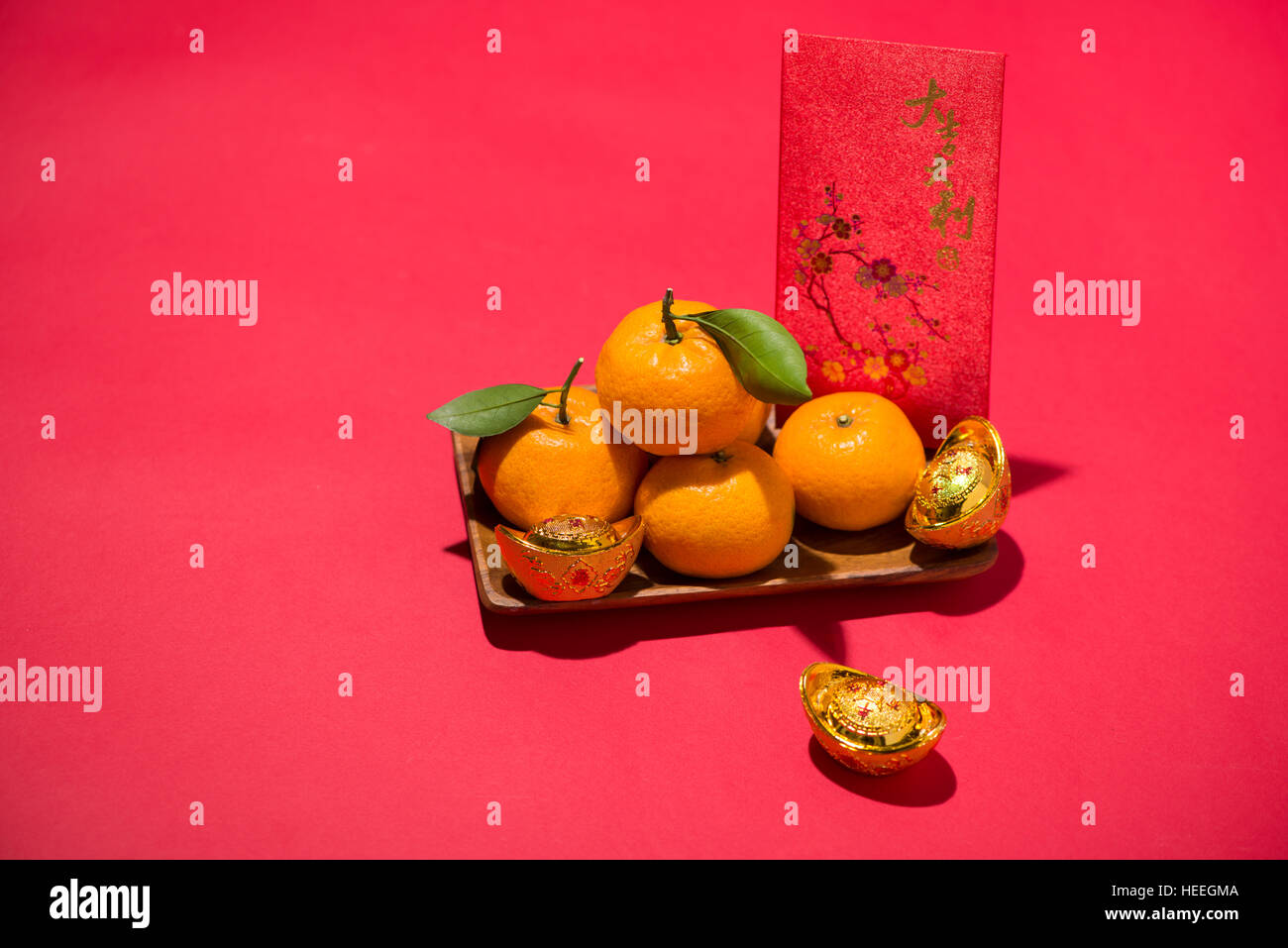 Chinesisches Neujahrsfest. Mandarine mit Angbao auf rotem Grund Stockfoto