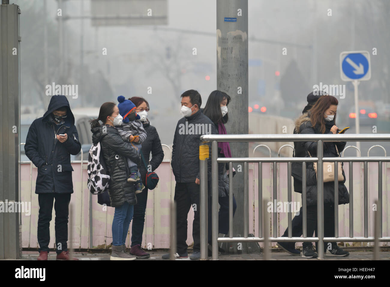 Bewohner mit Masken Bus warten, wie Beijing Großalarm für Smog in Peking, China. 20. Dezember 2016 Stockfoto
