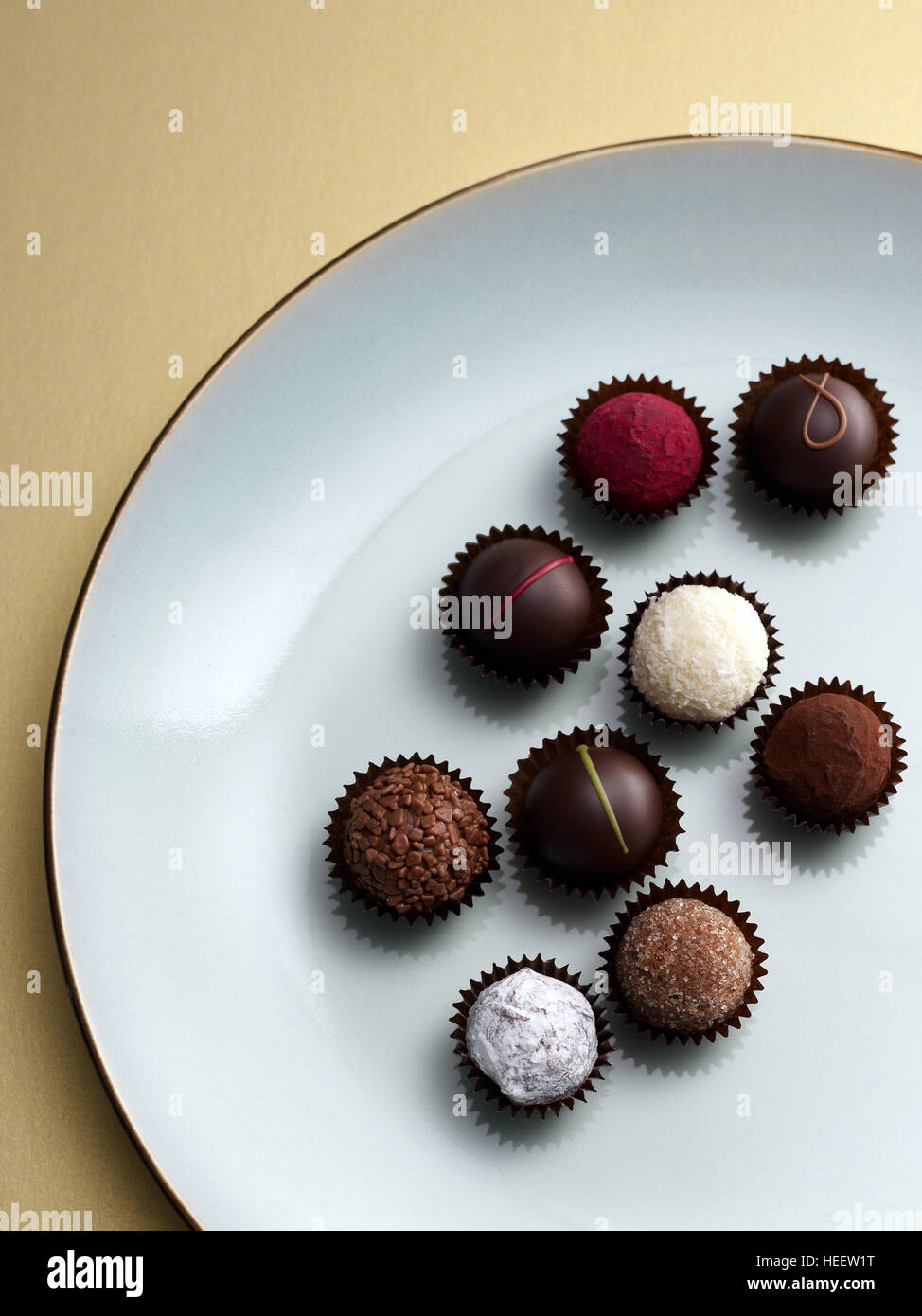 Pralinen und Trüffel auf blaue Platte und Goldgrund Stockfoto