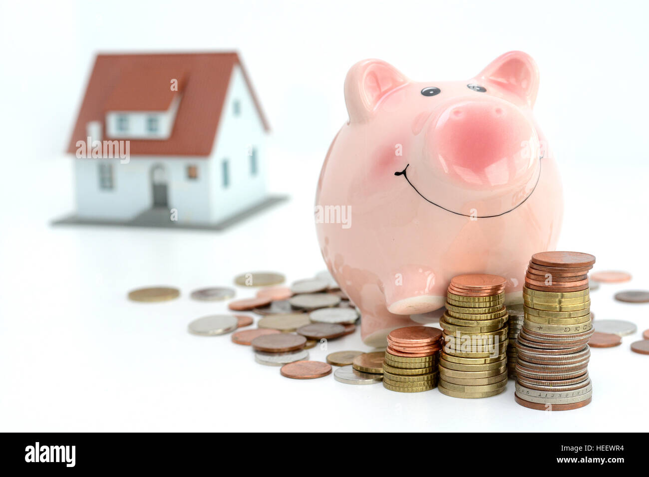 Einsparungen für Immobilien-Projekt mit kleinen Musterhaus und Sparschwein Klettern auf Berge von Münzen Stockfoto