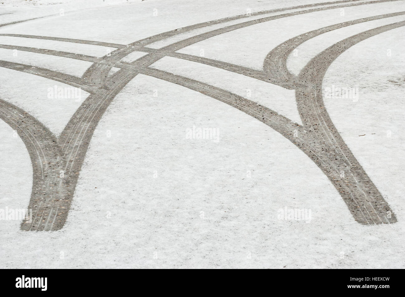 Reifenspuren / Markierungen im Neuschnee auf einer asphaltierten Straße. Stockfoto