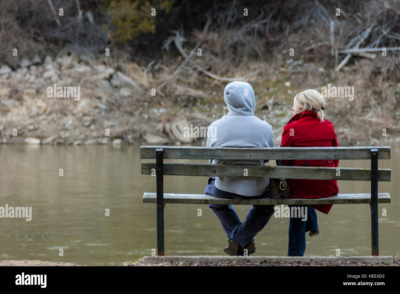 Ein junges Paar sitzt auf einer Parkbank im Herbst mit dem Rücken zur Kamera. Stockfoto