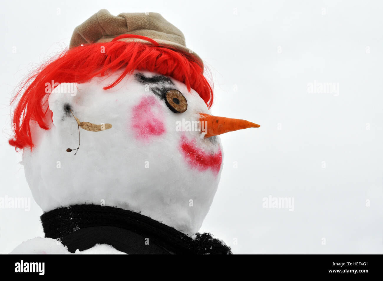 Nahaufnahme der Schneemann mit roter Perücke, schwarzen Schal und Mütze Stockfoto