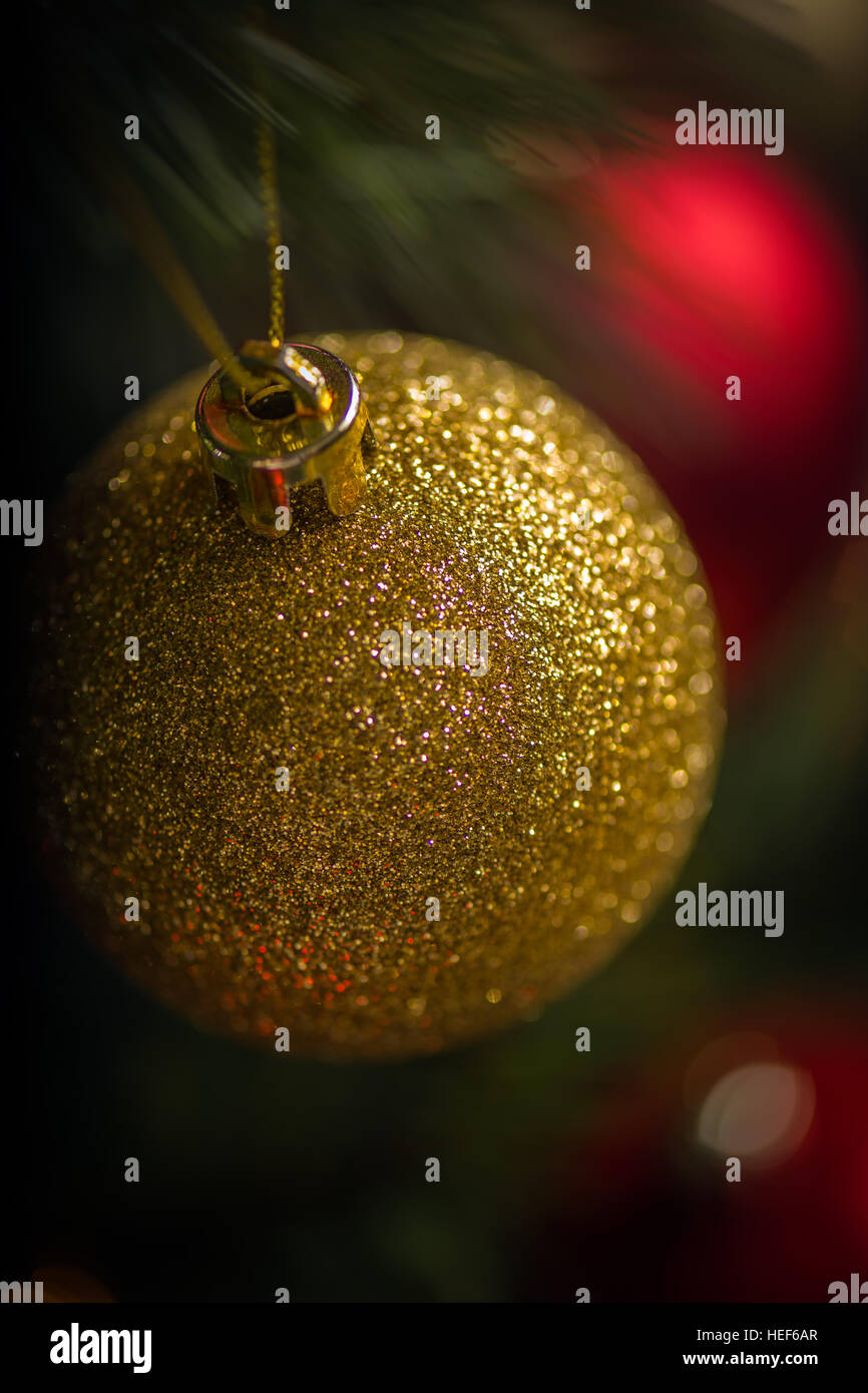 Rote und goldene Kugeln heben sich gegen die Lichter am Weihnachtsbaum. Stockfoto