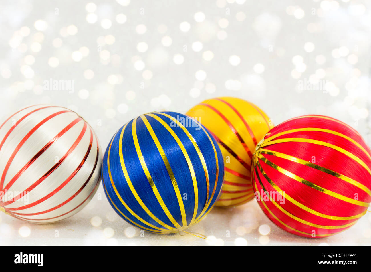 drei bunte Weihnachtskugeln mit goldenen Linien auf weißem Stockfoto