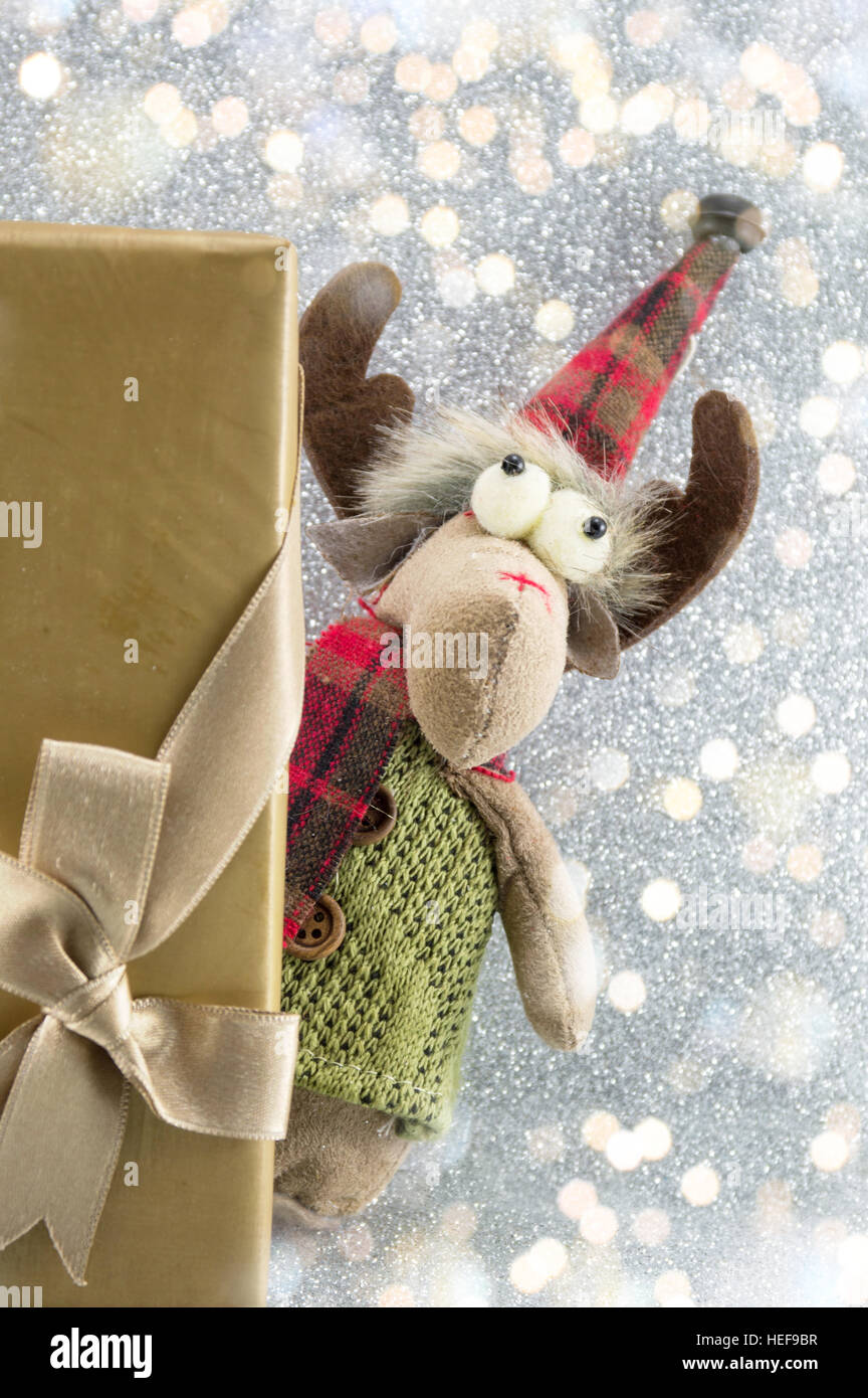 Spielzeug Rentier versteckt sich hinter Weihnachtsgeschenk Stockfoto
